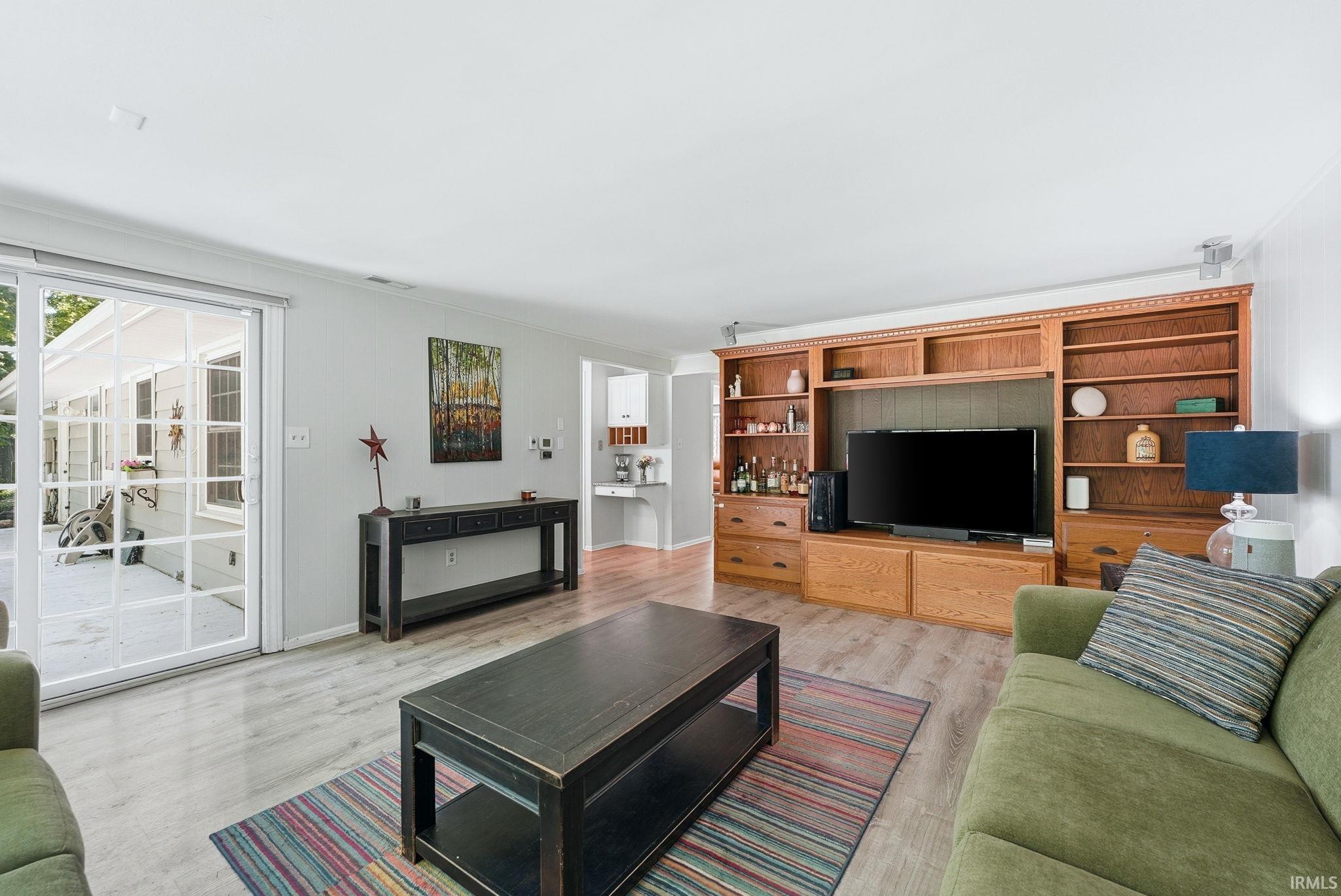 Living area featuring wood-finish flooring and a built-in entertainment center with shelving and storage