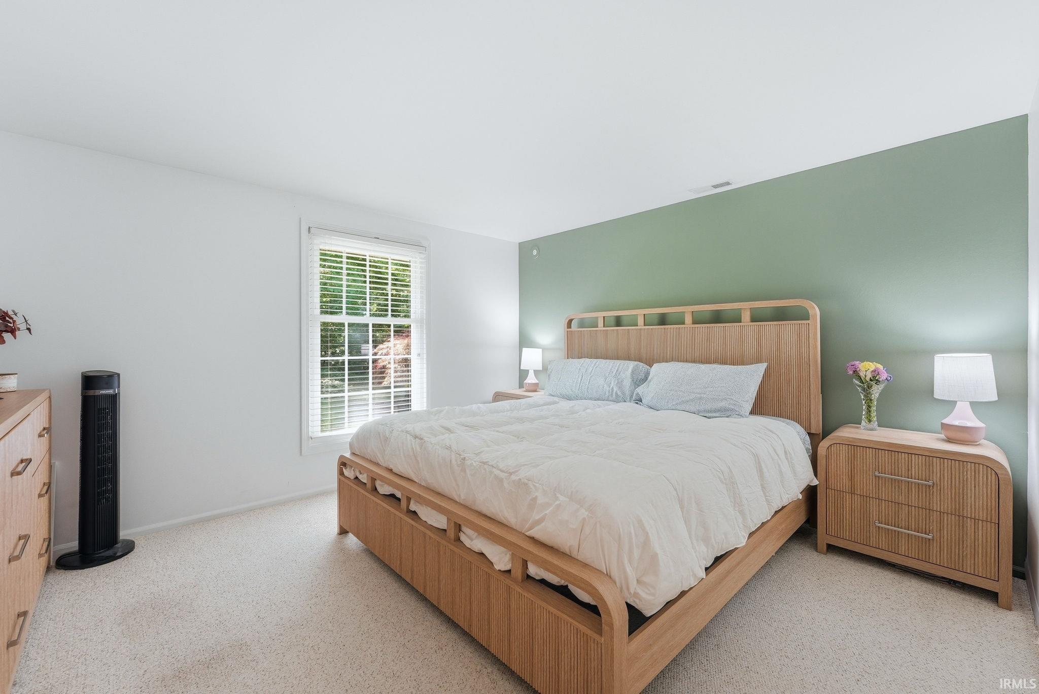 Bedroom featuring light-toned carpeting and a window with white blinds