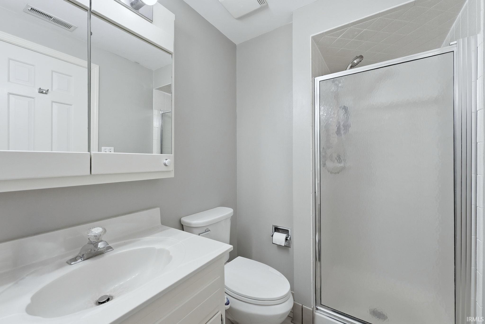 Bathroom featuring a white vanity with integrated sink, chrome faucet, and a wall-mounted medicine cabinet with mirrored doors