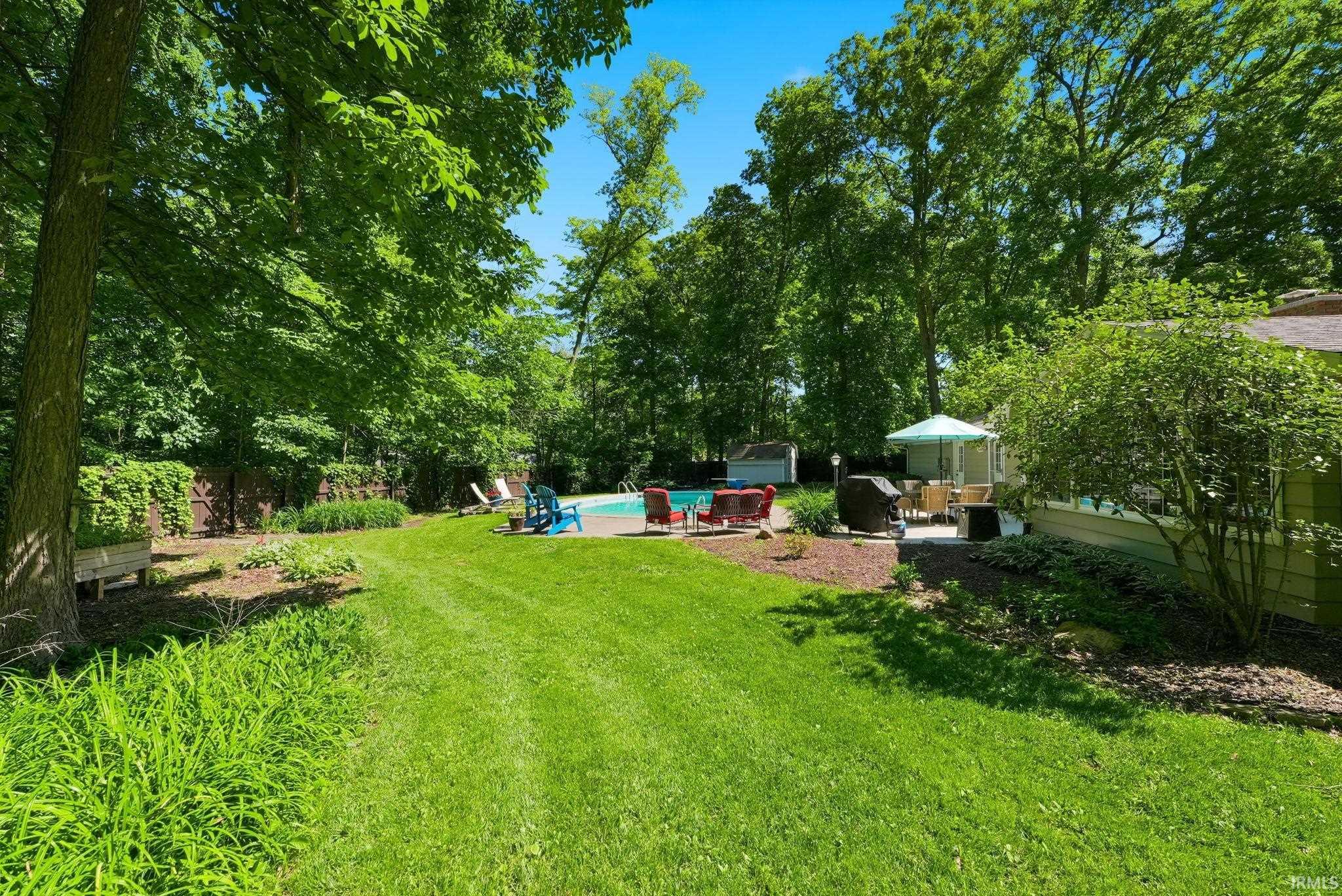 Expansive backyard featuring a manicured lawn, inground swimming pool, and concrete patio