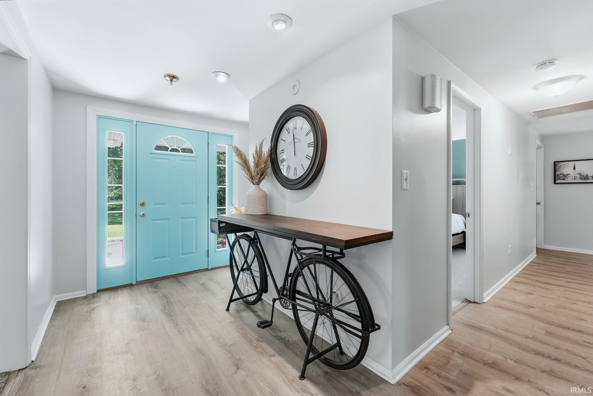Entryway featuring a bright blue paneled door with an arched transom window and sidelights, light wood-finish flooring, recessed lighting, and white baseboards