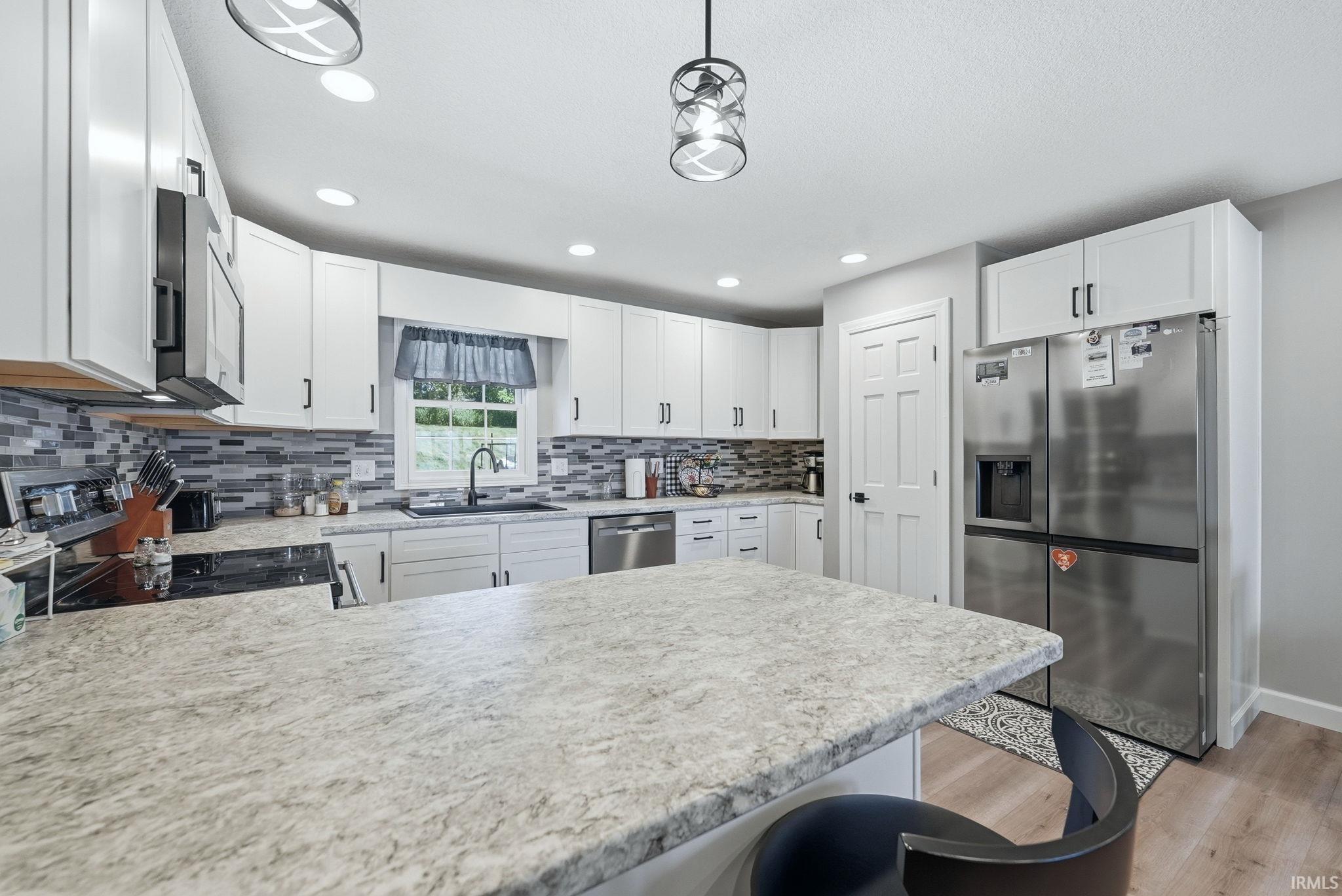 Spacious kitchen featuring white cabinetry, light-toned countertops, and a full tile backsplash