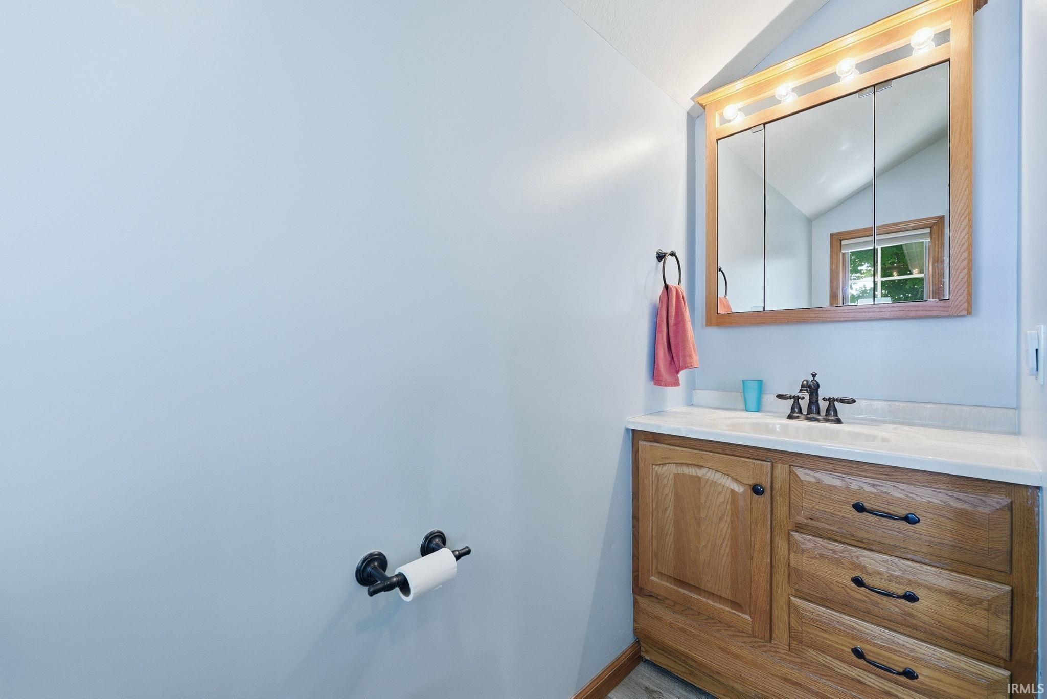 Bathroom vanity featuring wood-finish cabinetry, a white countertop, and an integrated sink