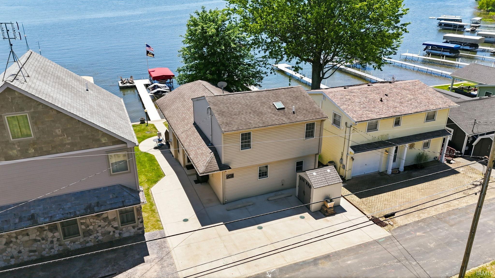 Waterfront property featuring a private boat dock, concrete driveway, and a detached storage shed