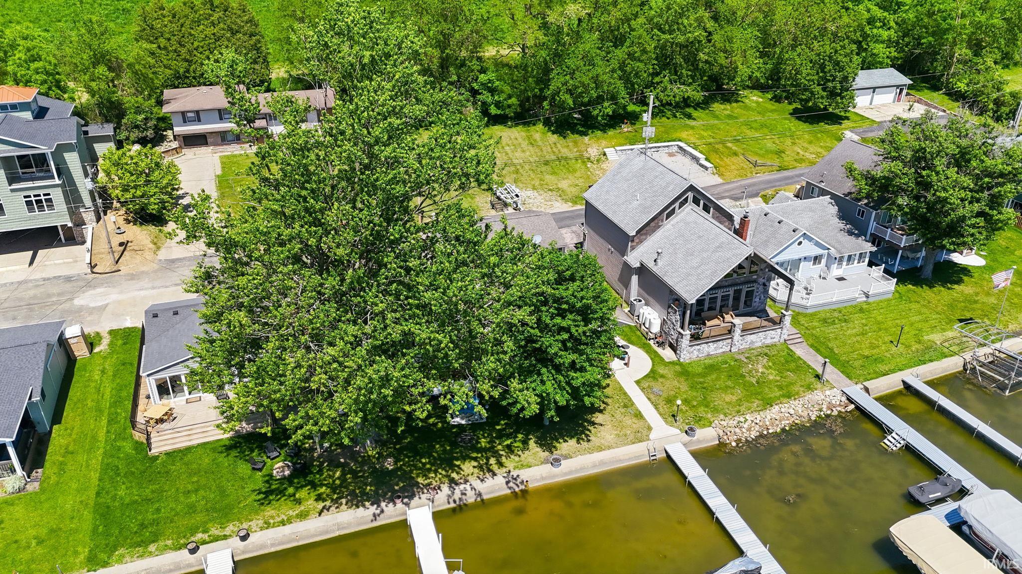 Waterfront property featuring multiple boat docks, a stone-clad porch, and a lush green lawn