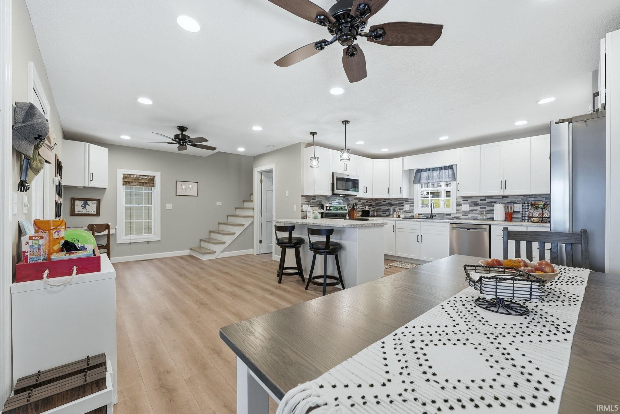 Open-concept living area featuring wood-finish flooring, recessed lighting, and ceiling fans