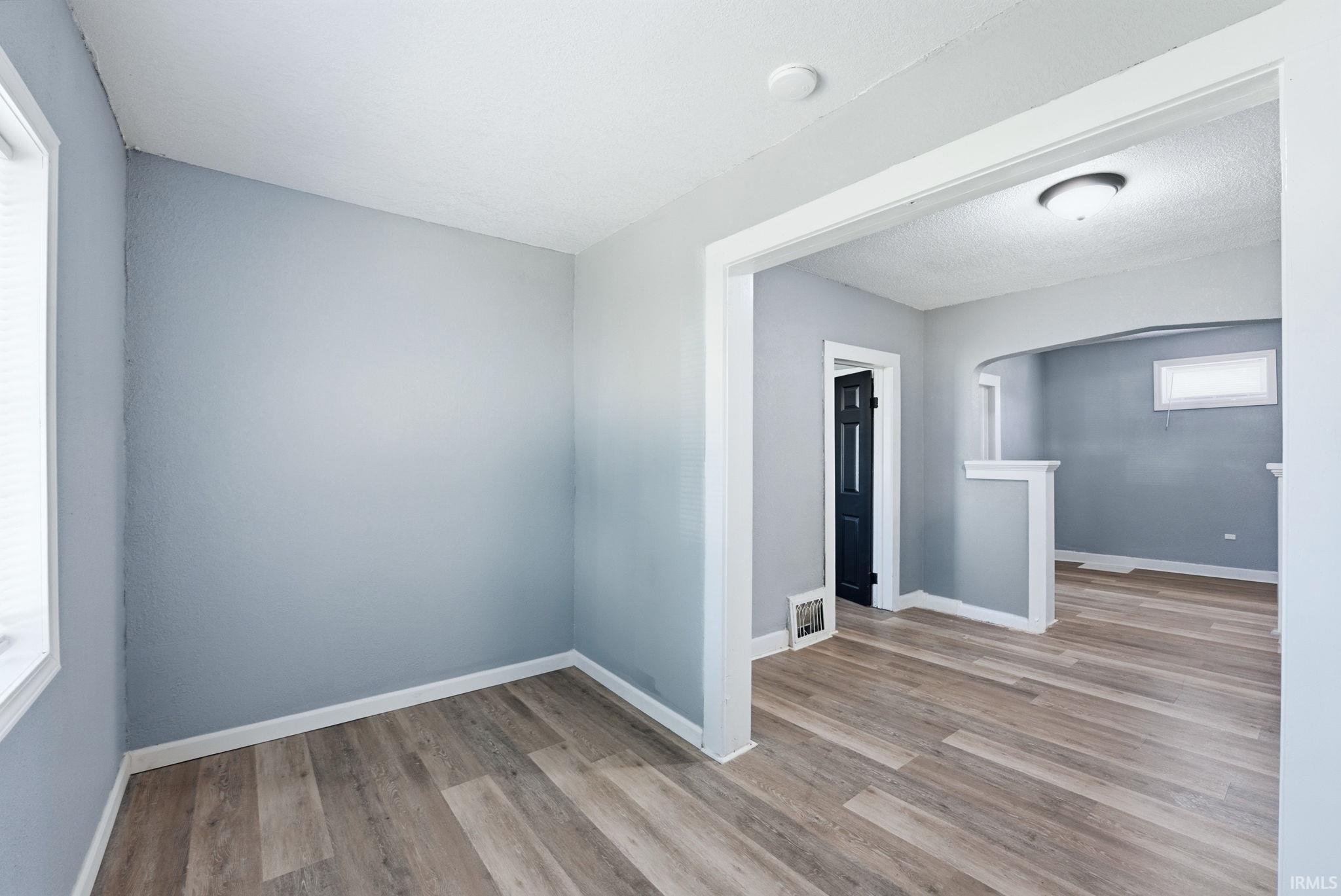 Interior space featuring light gray walls, wood-finish flooring, white baseboards, and a white ceiling with recessed lighting