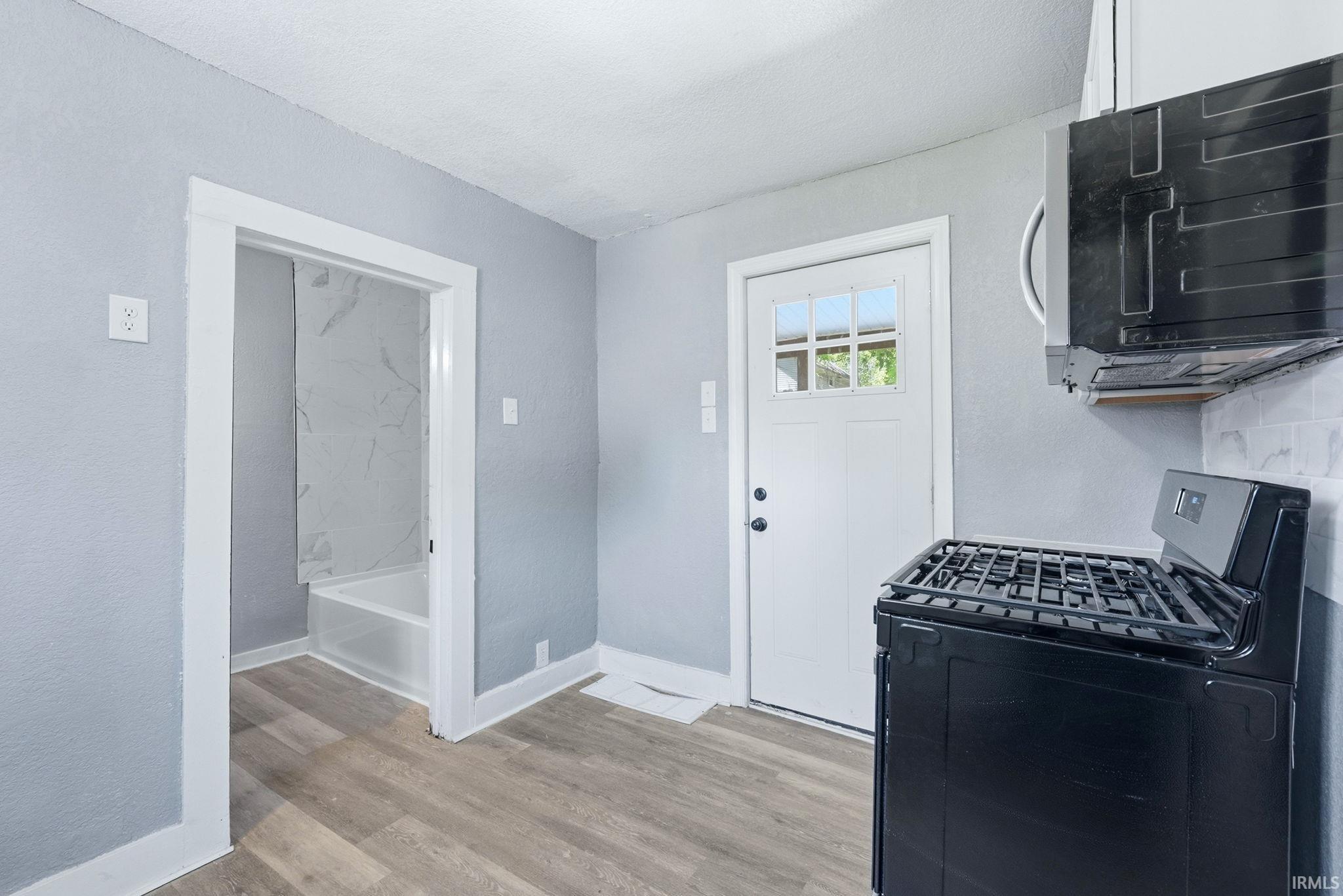 Kitchen area featuring a modern black range, white subway tile backsplash, and light wood-finish flooring