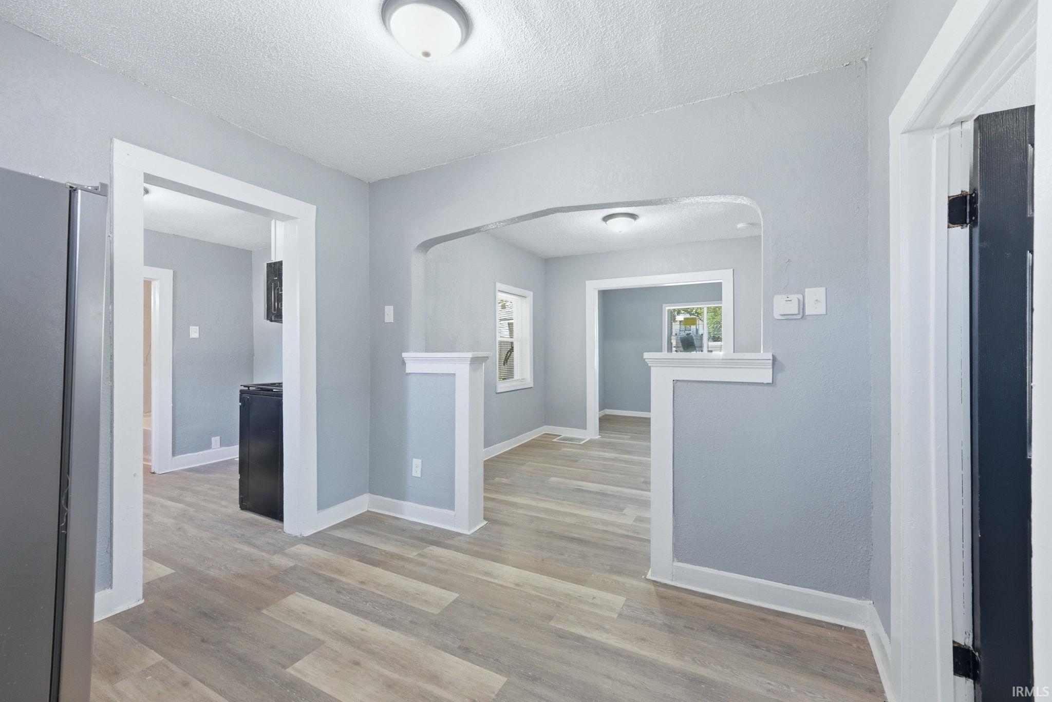 Open concept living spaces featuring wood-finish flooring, light gray wall tones, and white trim