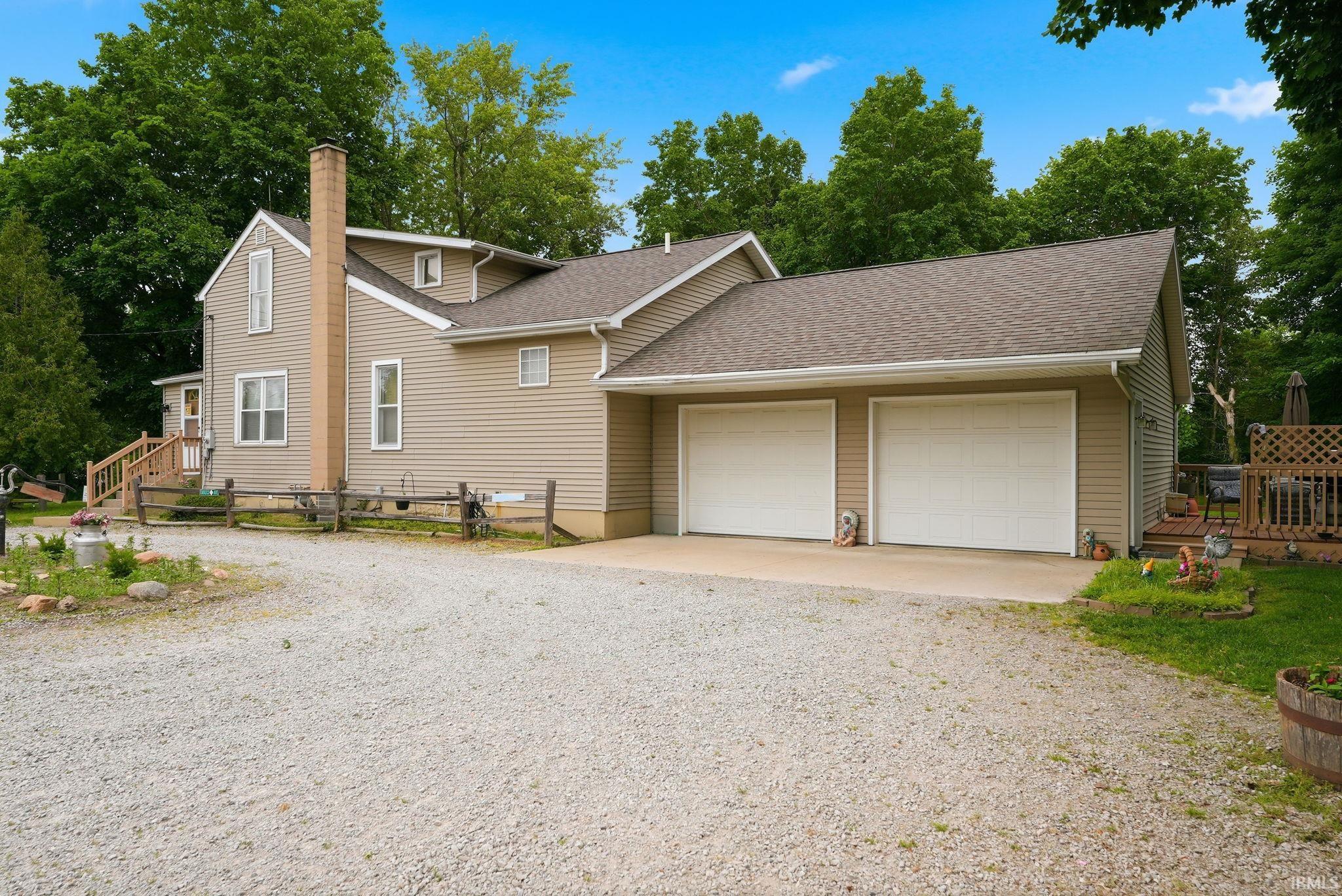 Exterior featuring tan siding, a prominent chimney, and a dual-door attached garage