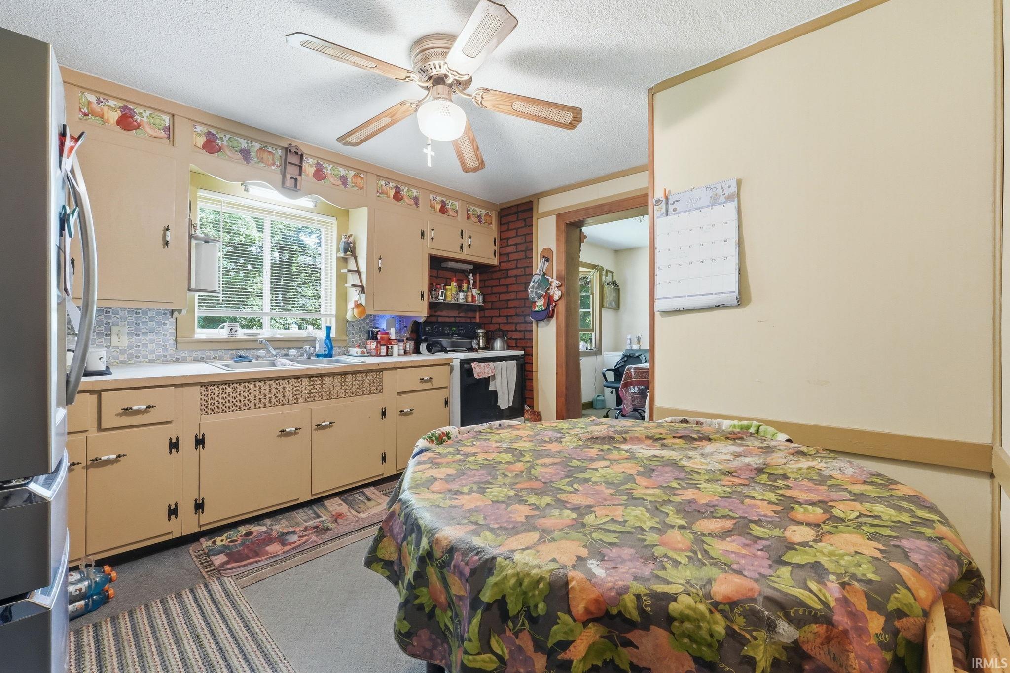 Kitchen featuring wood-finish cabinetry, a window over the sink, and a ceiling fan with light fixture