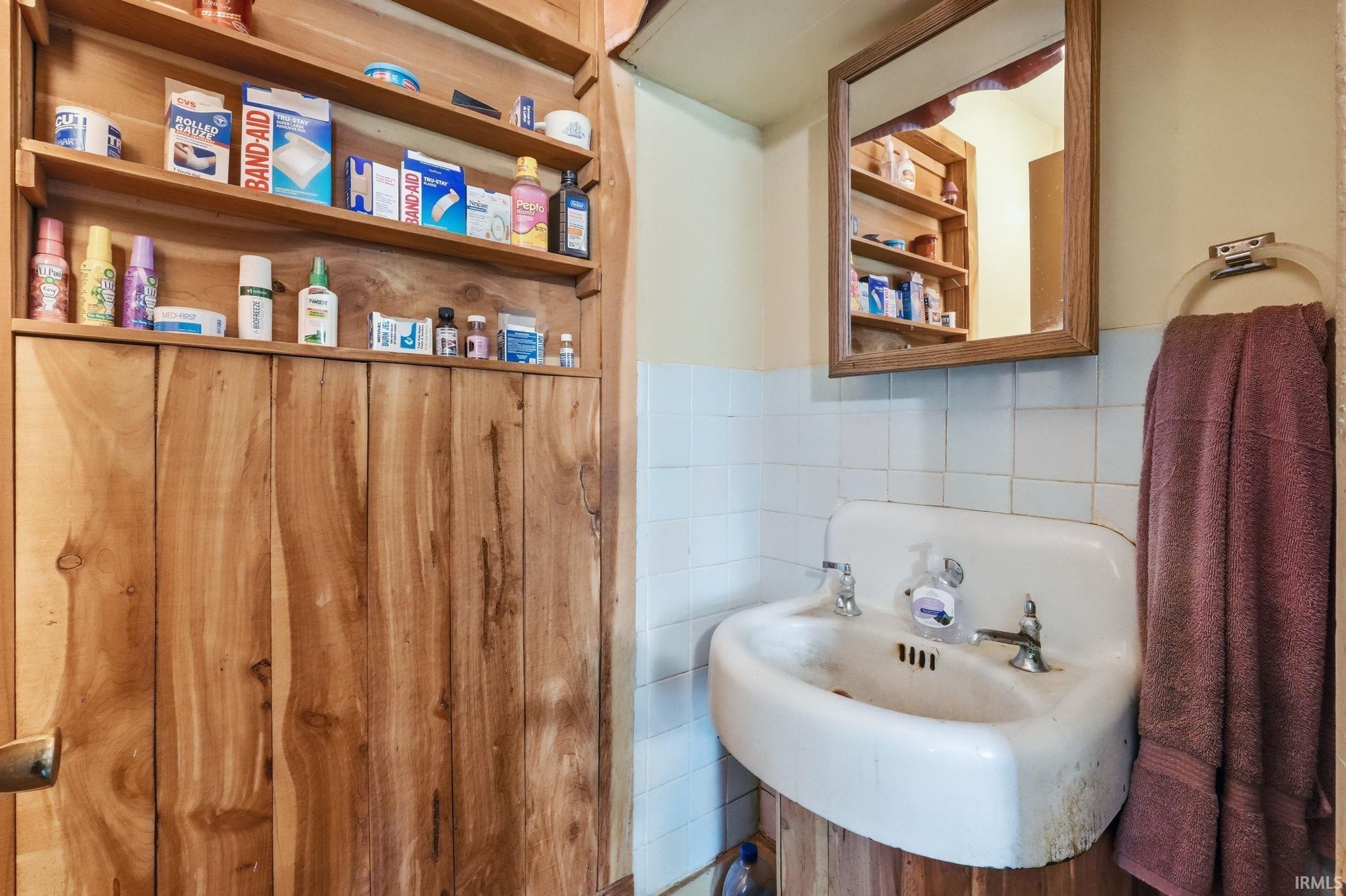 Pedestal sink featuring dual basin faucets and a wall-mounted mirror