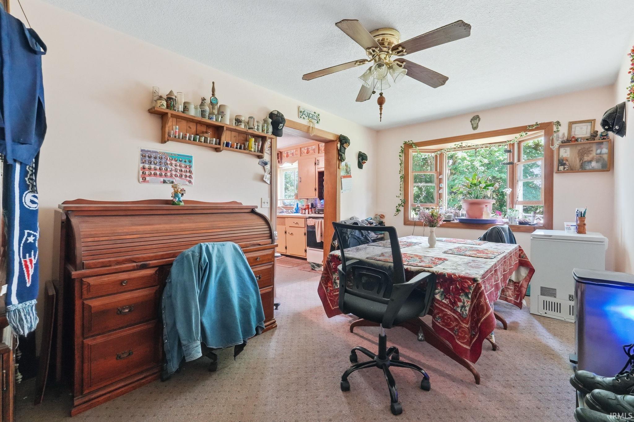 Spacious room featuring a bay window, ceiling fan, and carpeted flooring