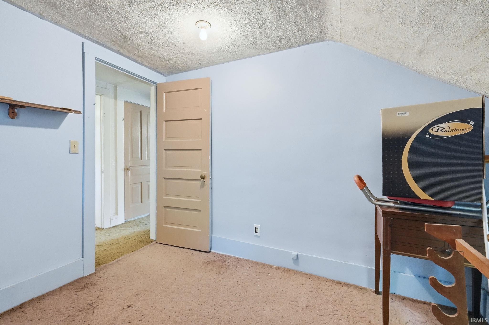 Carpeted room with a five-panel interior door and light blue wall paint