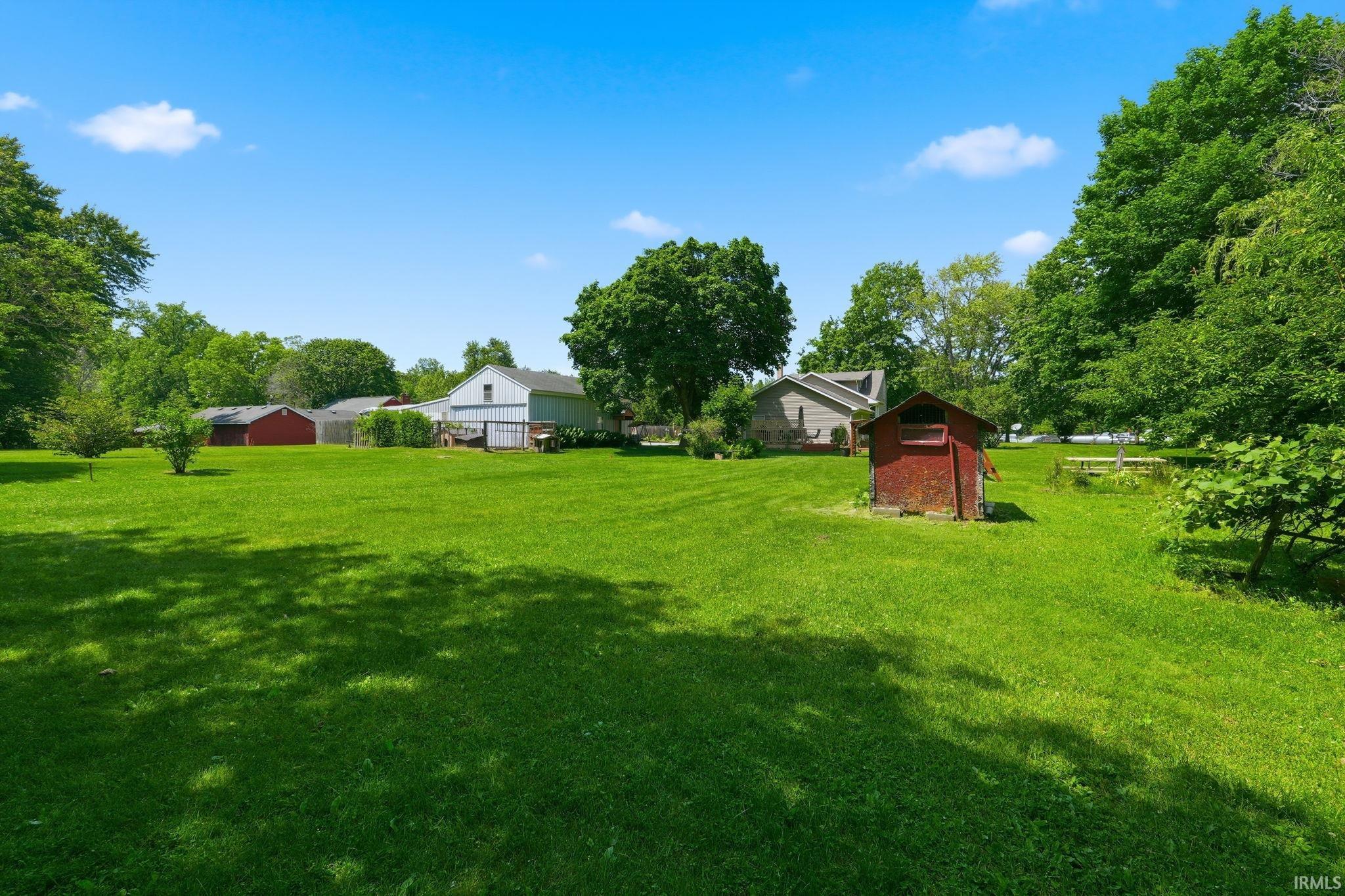 Expansive green lawn with mature trees and a red accessory structure
