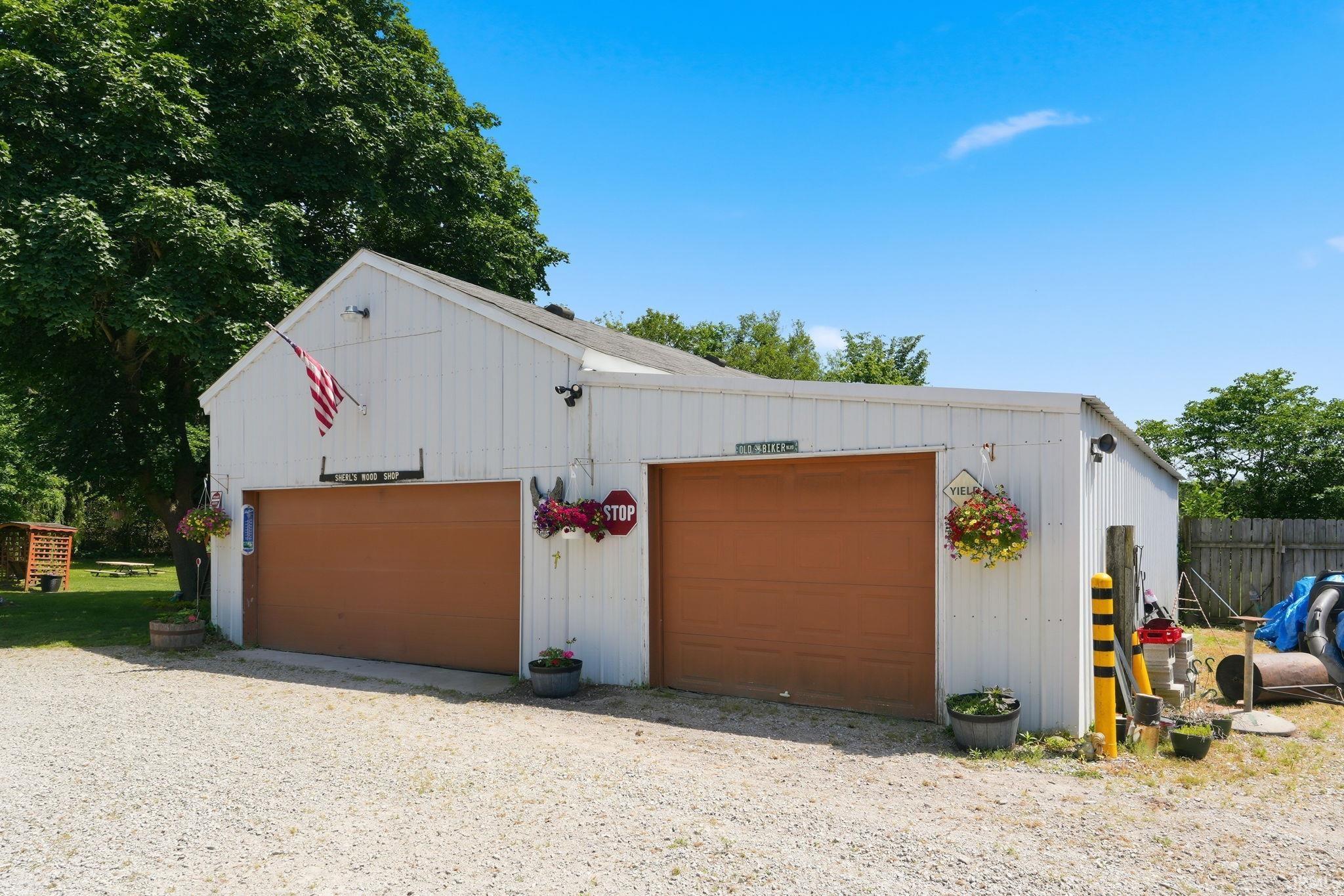 Detached two-bay garage structure with white vertical siding and brown garage doors