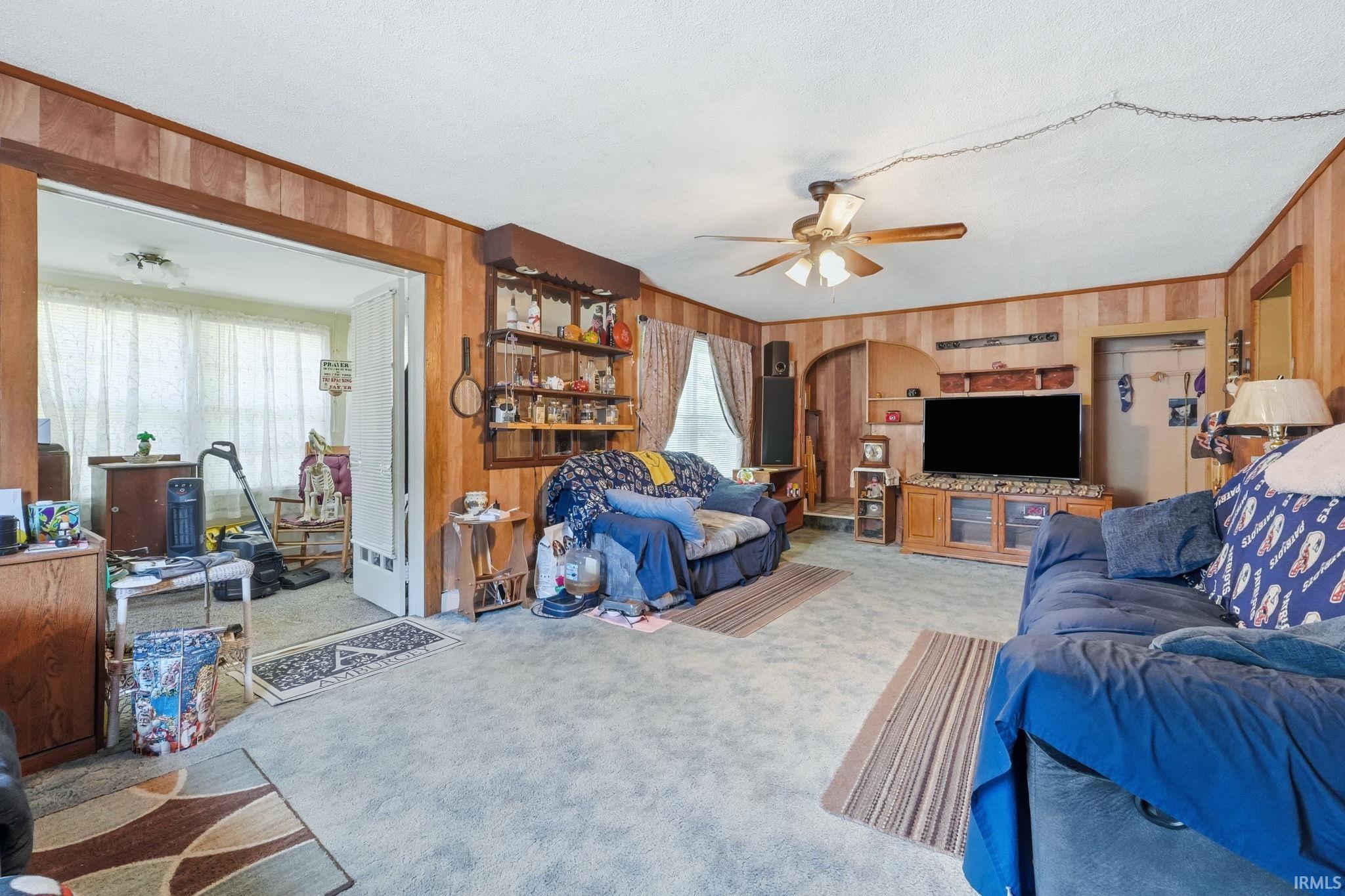 Living area featuring wood-paneled walls and light-toned carpeting