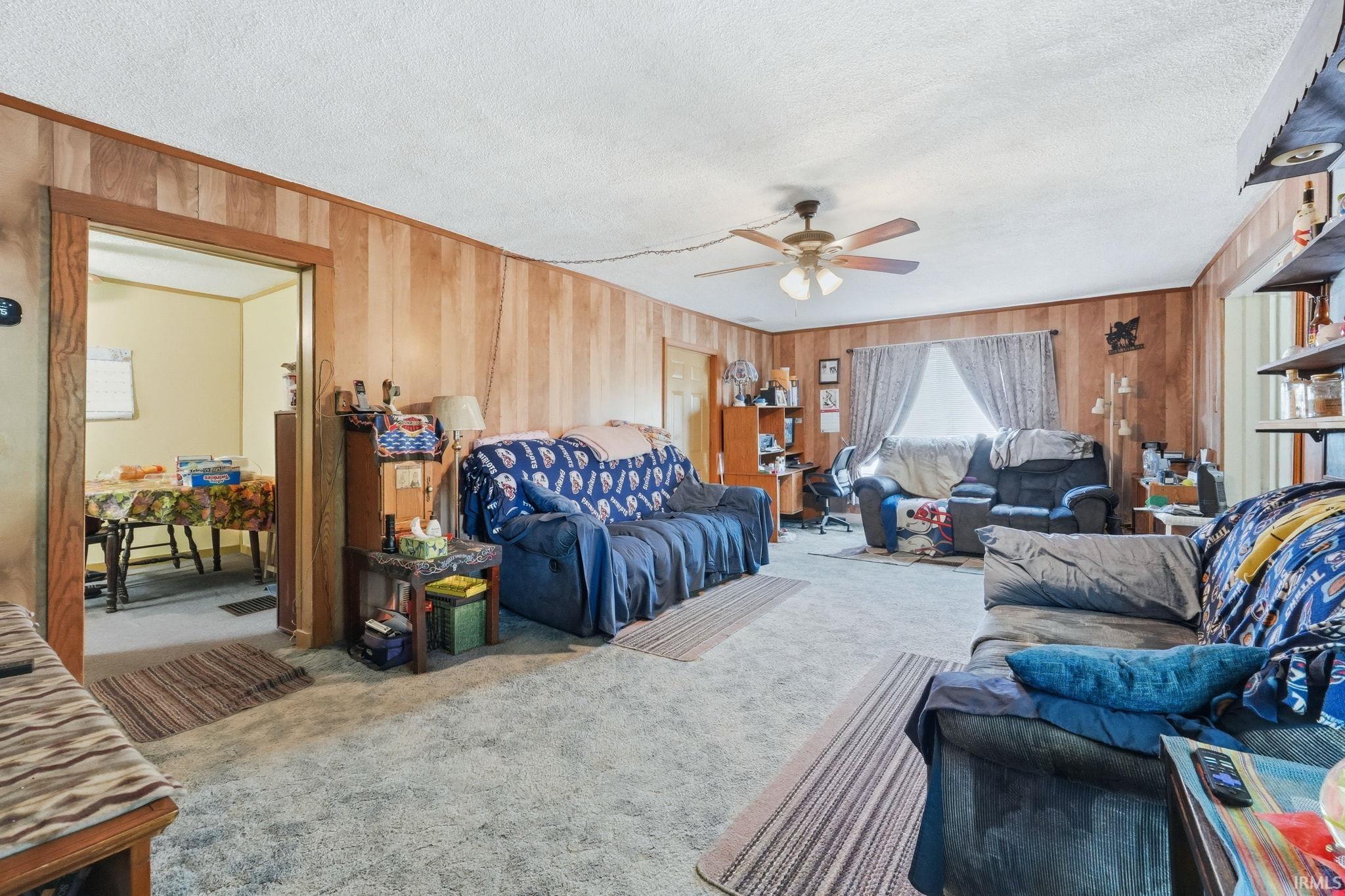 Spacious living area featuring vertical wood paneling and a light-colored ceiling