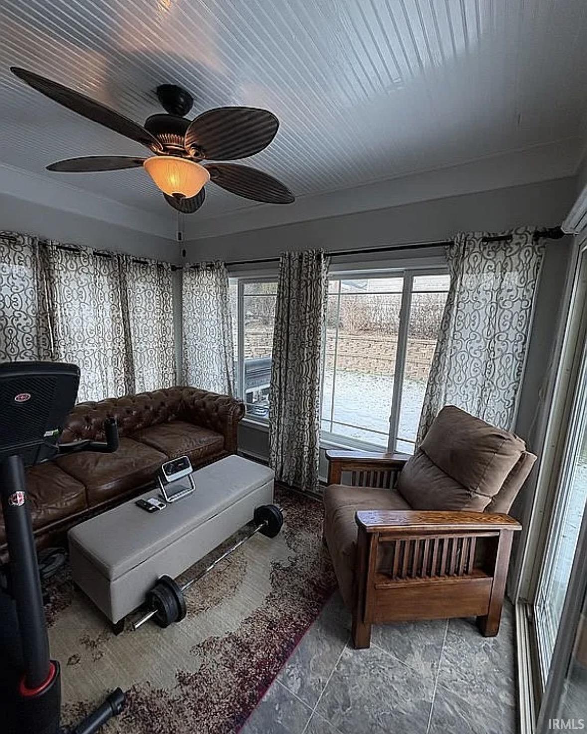 Sunroom featuring a beadboard ceiling, ceiling fan with integrated lighting, and multiple windows