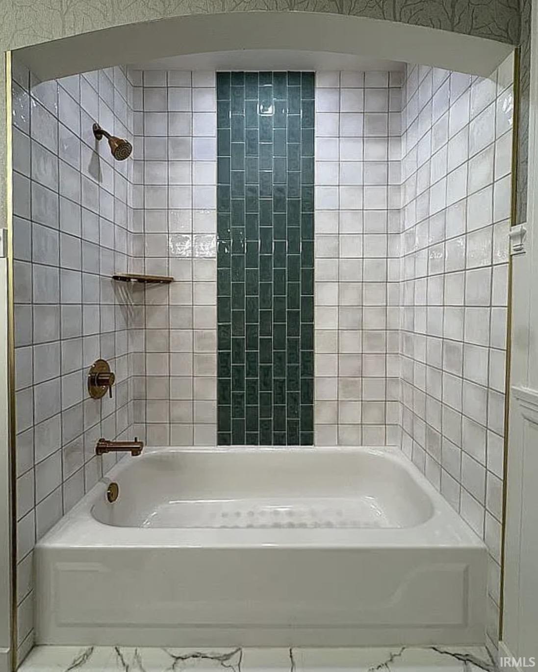 Bathtub and shower combination featuring white subway tile, a vertical accent of dark green subway tile, and bronze fixtures