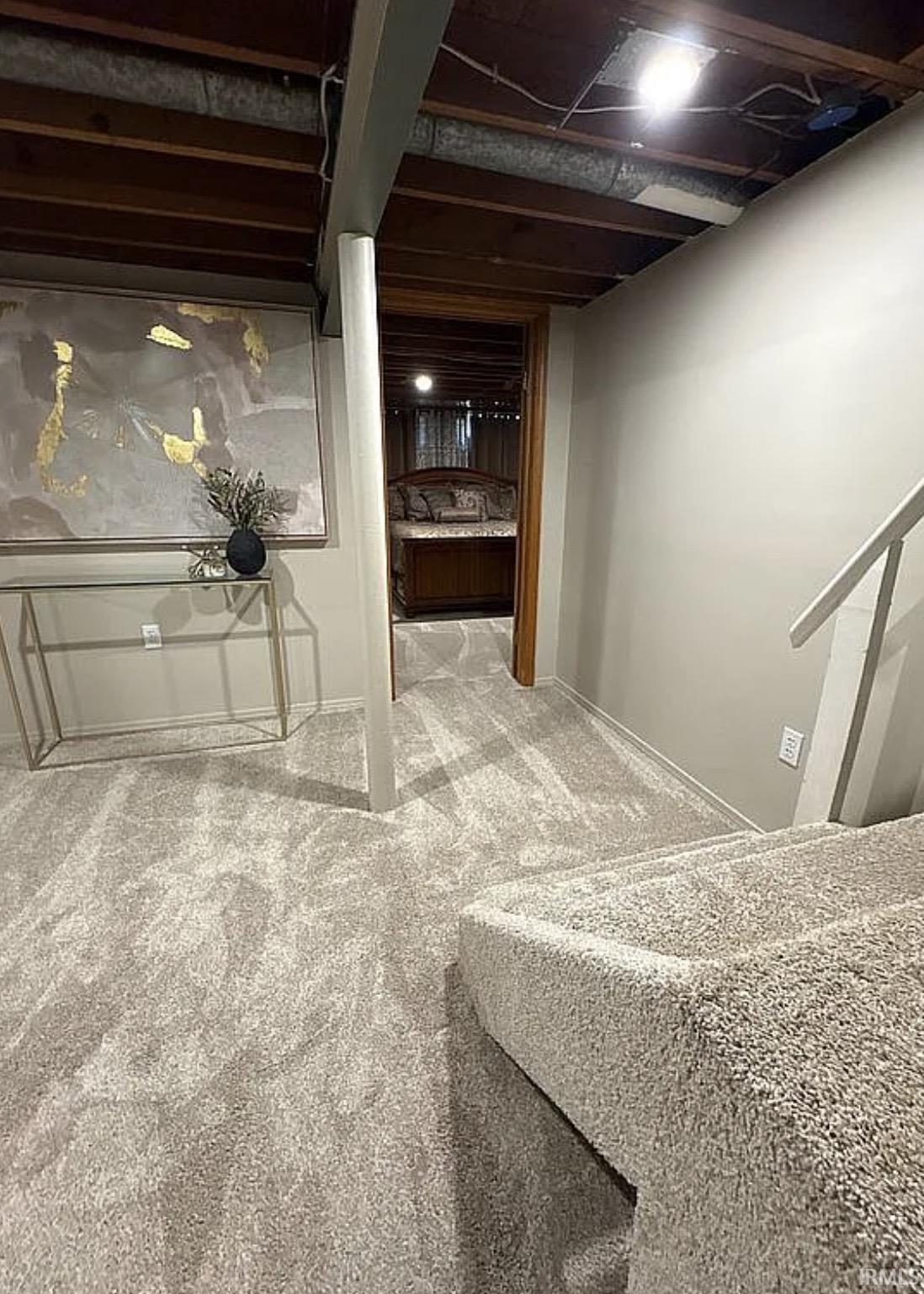 Plush carpeted flooring throughout the space, with neutral wall paint and a finished staircase