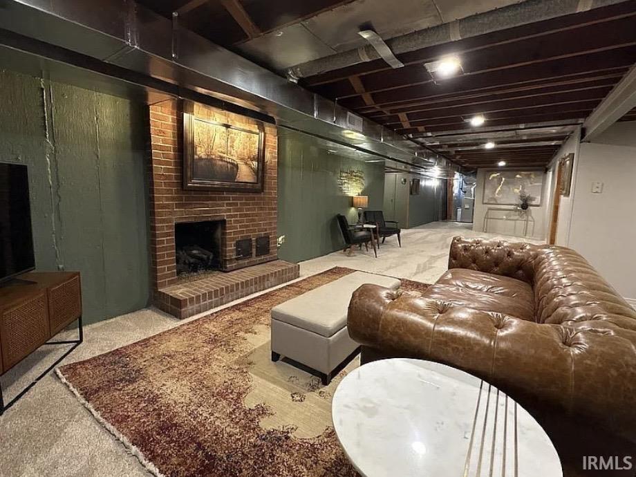 Finished lower level featuring a brick fireplace, exposed ceiling beams, and recessed lighting