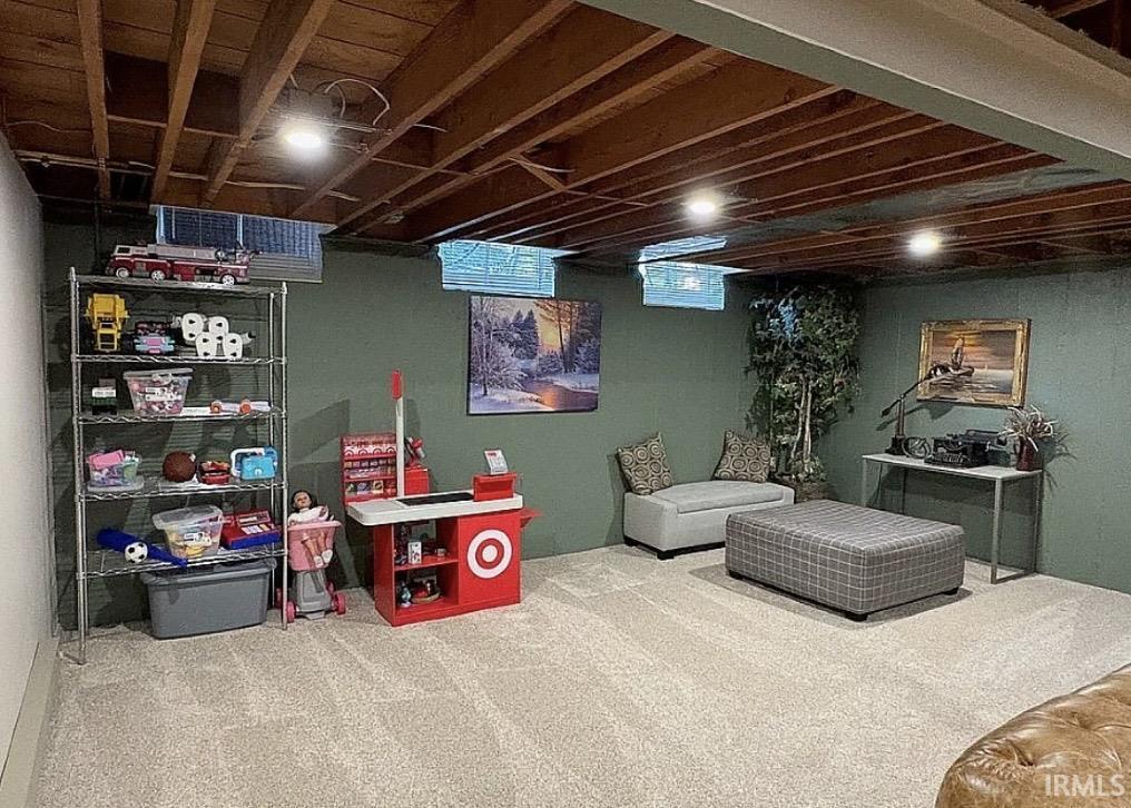 Carpeted lower-level space featuring a painted wall finish, exposed ceiling joists, and recessed lighting