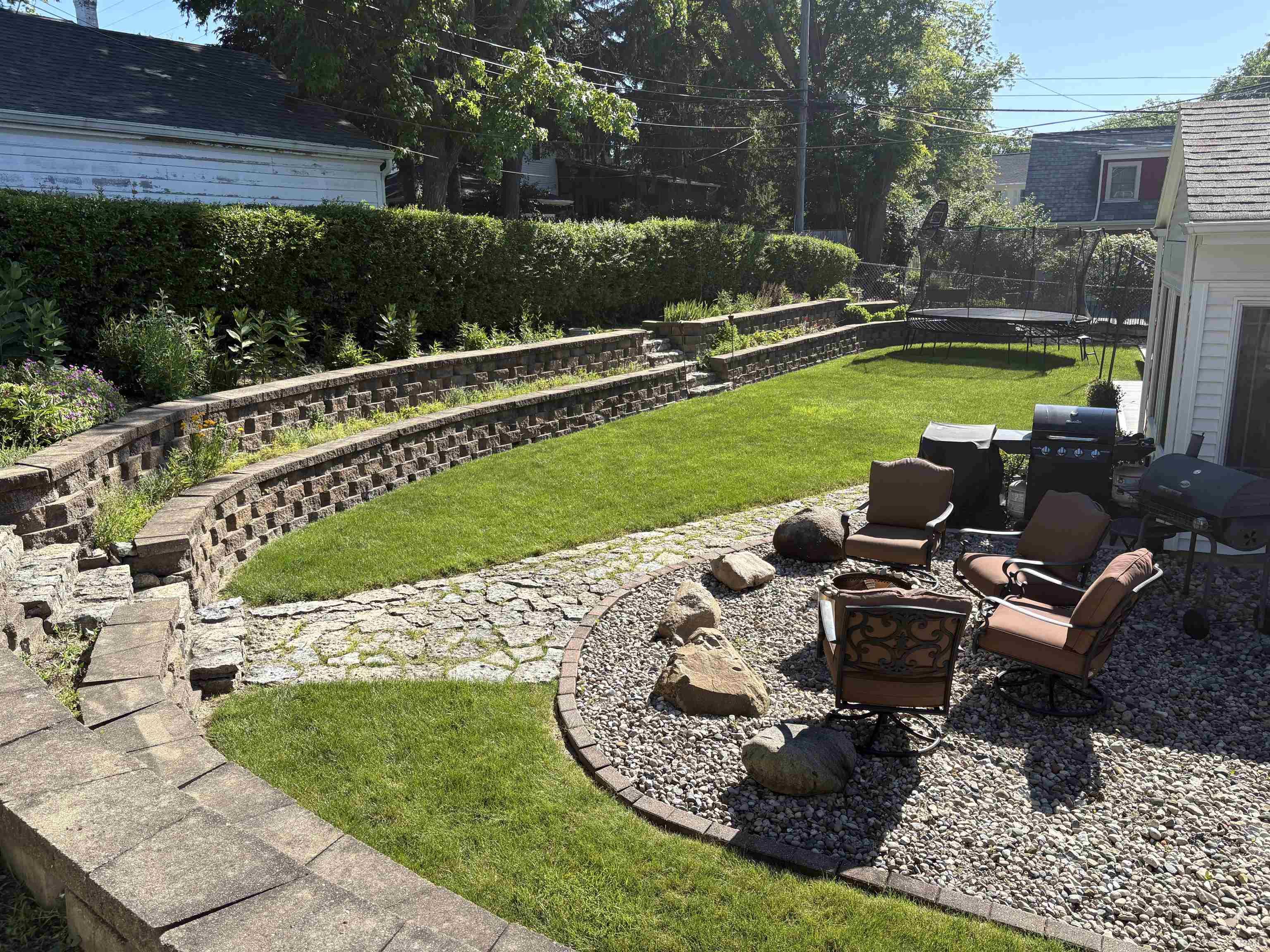 Expansive backyard featuring a tiered retaining wall system with integrated planting beds