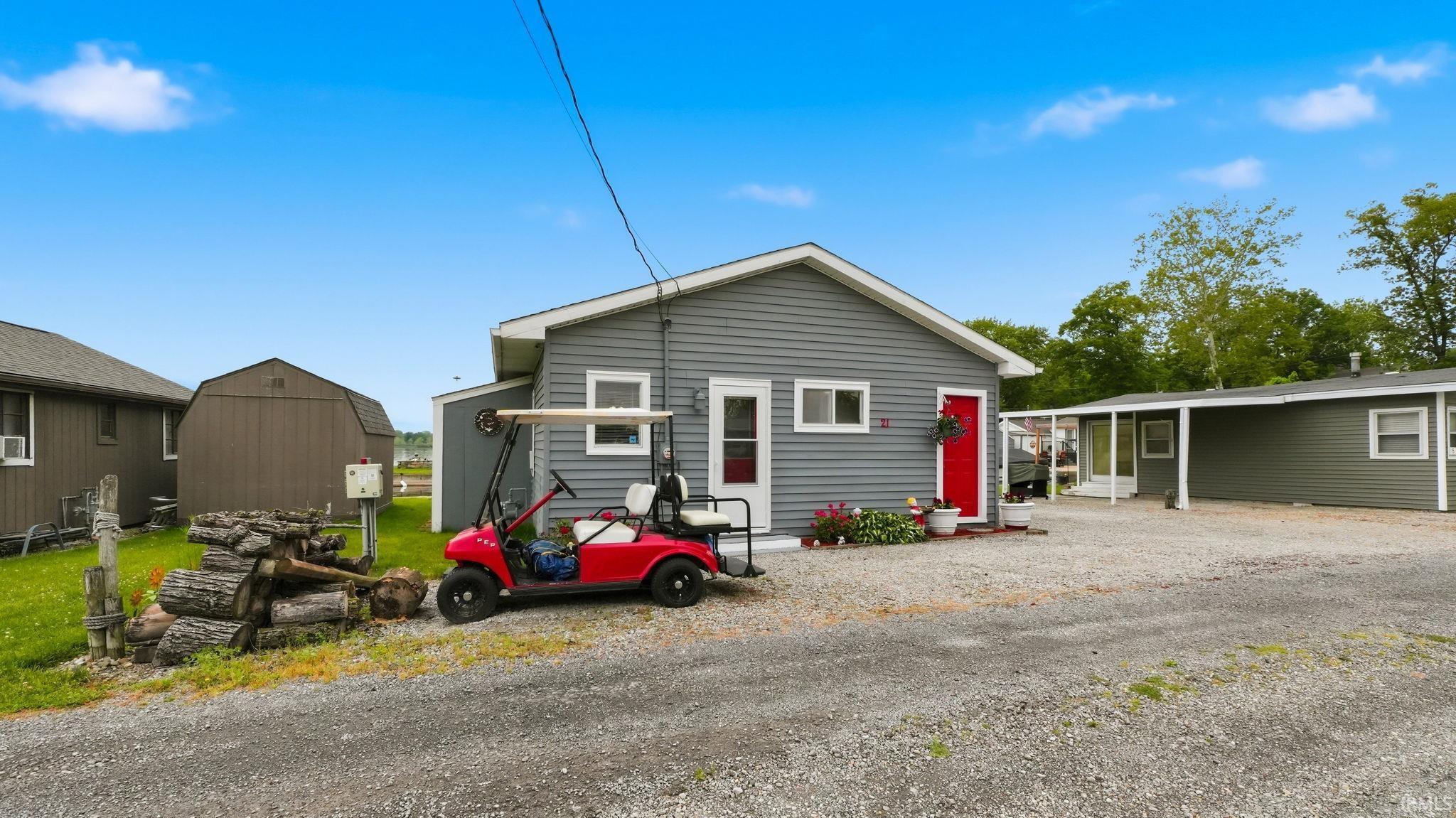 Gray siding exterior with a bright red entry door and white trim windows