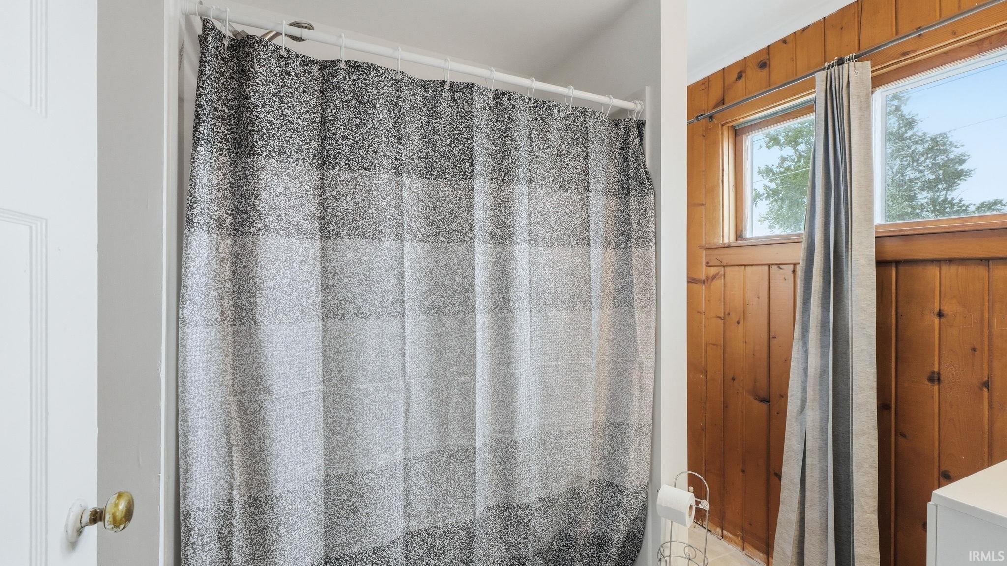 Bathroom featuring natural wood paneling, two windows with wood trim, and a white vanity base