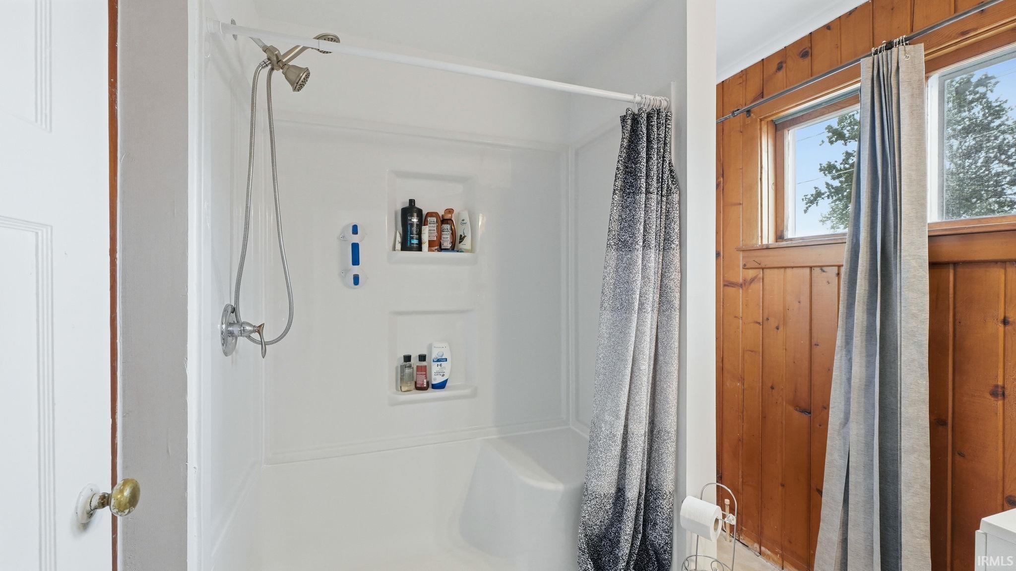 Shower enclosure featuring integrated shelving and a handheld showerhead