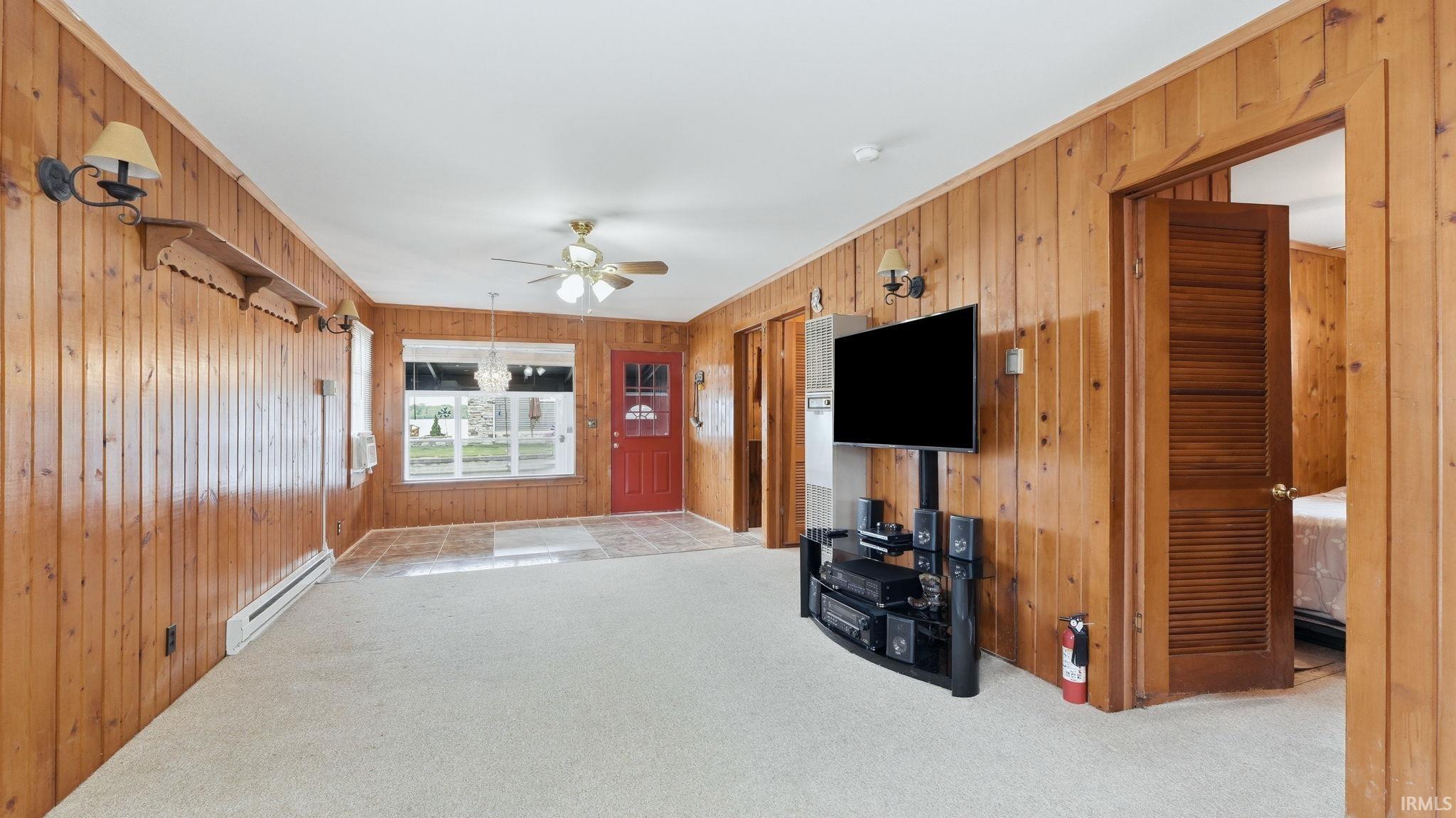 Spacious interior room featuring wood paneling, wall-mounted sconces, and a ceiling fan