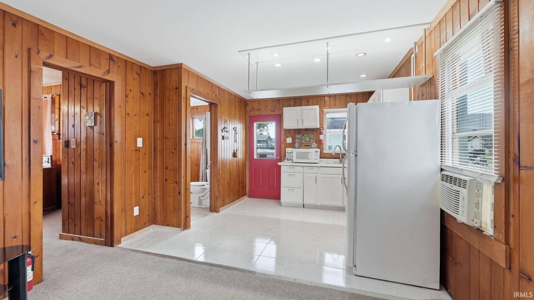 Compact kitchen featuring white cabinetry, a white refrigerator, and a built-in microwave
