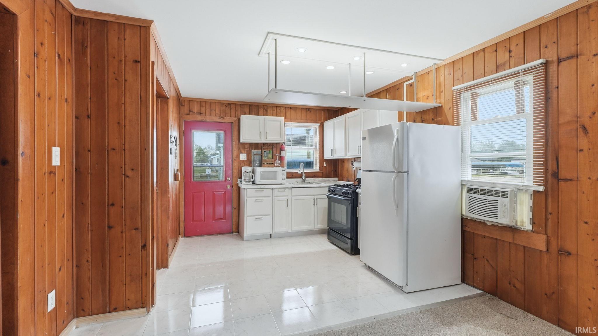 Kitchen featuring wood-paneled walls, white cabinetry, and white tile flooring