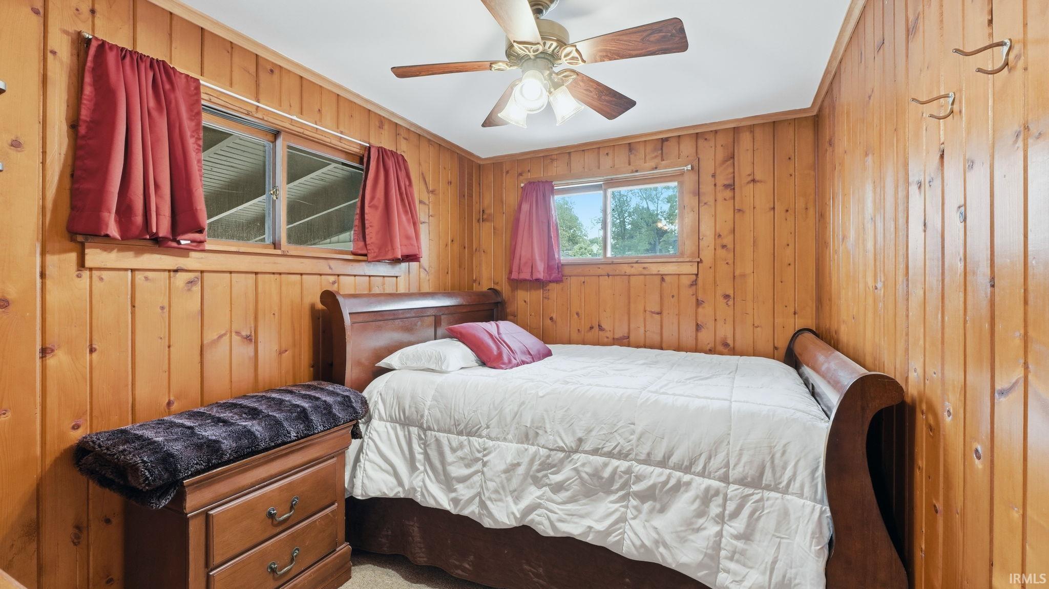 Wood-paneled room featuring two windows and a ceiling fan