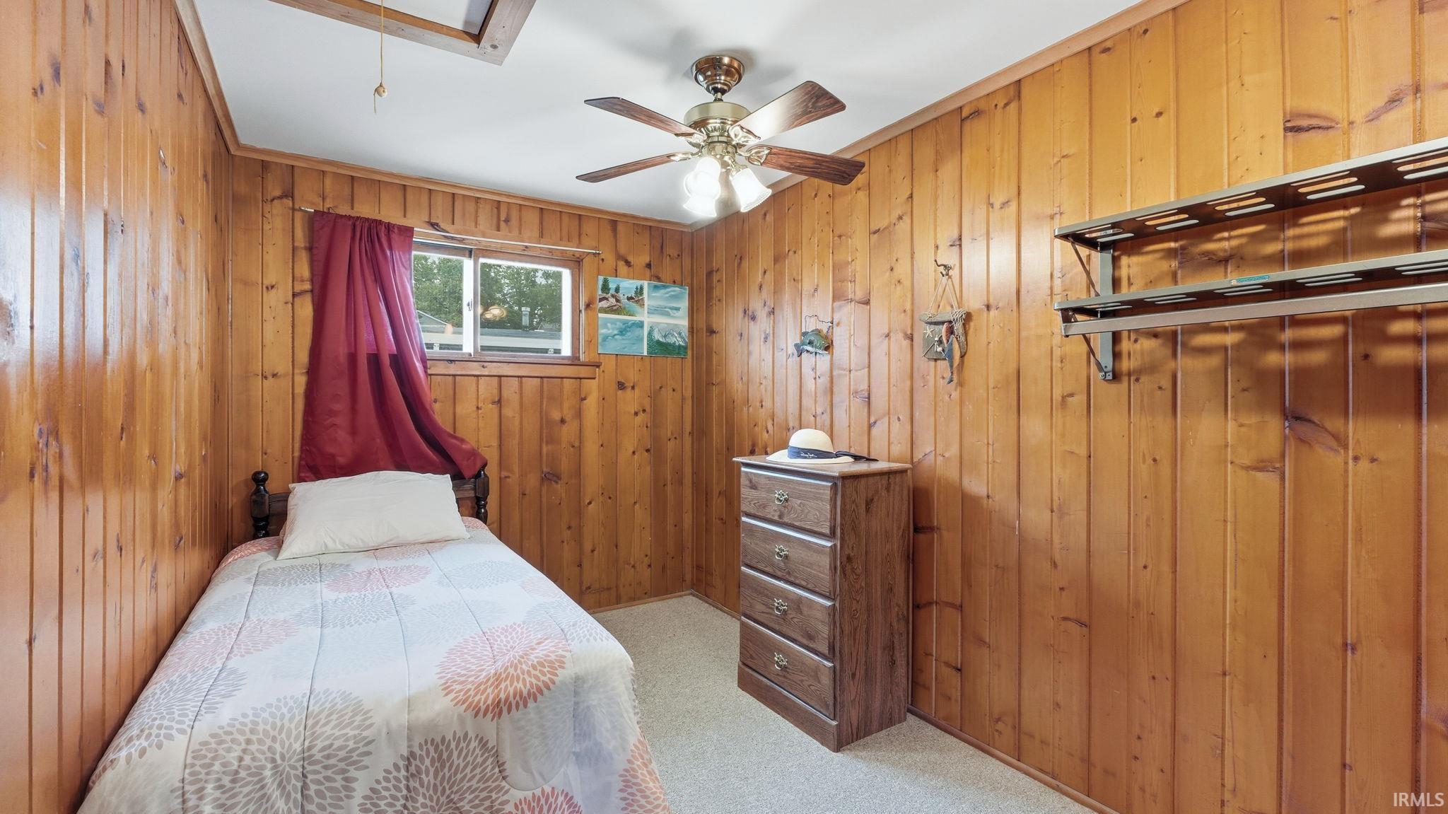 Wood-paneled room featuring a ceiling fan with integrated lighting, a window, and built-in shelving