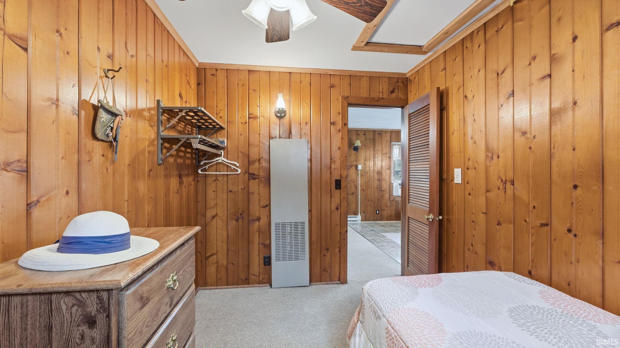 Room featuring wood paneling throughout, a louvered interior door, and a built-in wall heater