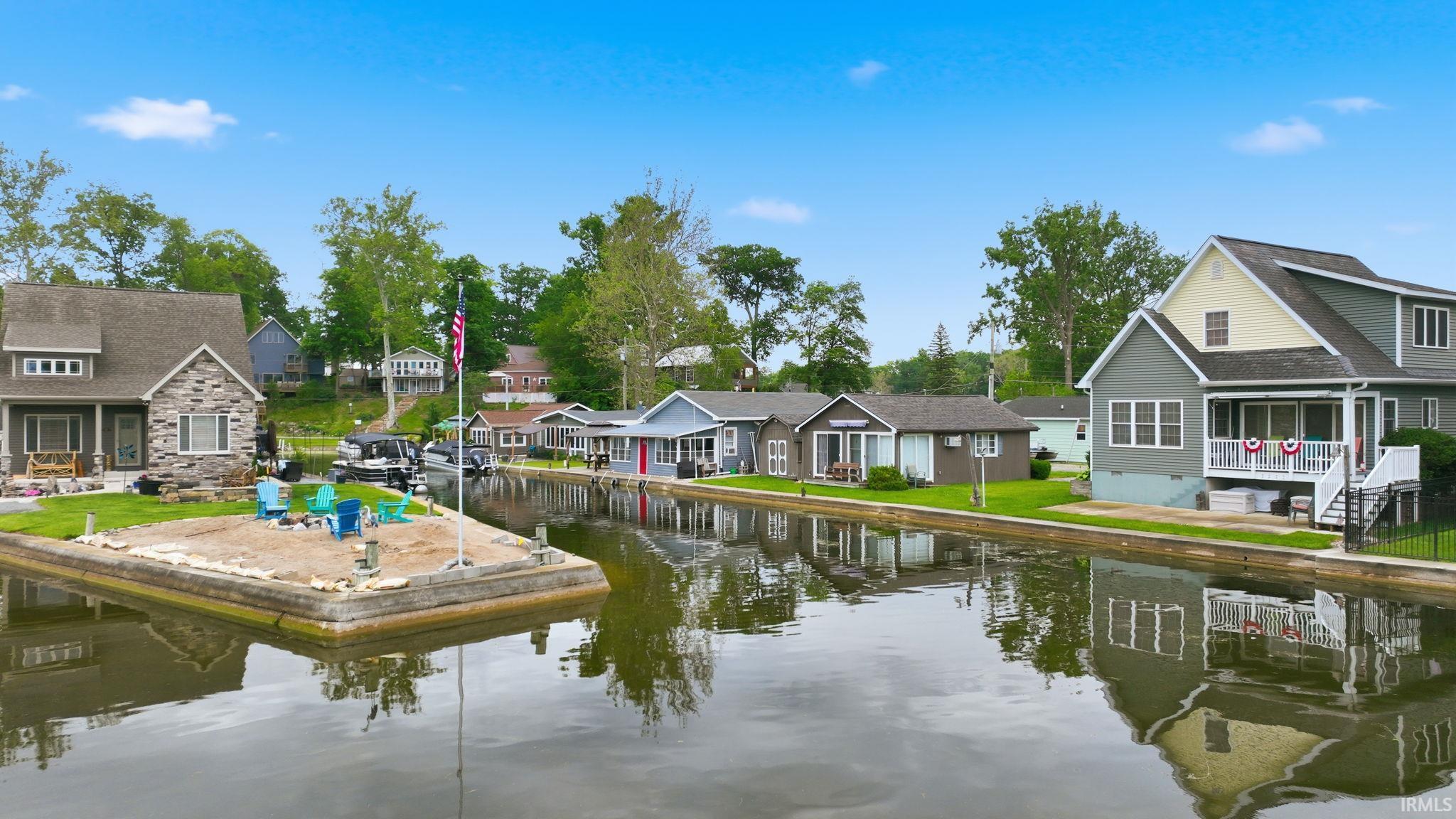 Waterfront property featuring canal access, stone and siding exterior, multiple levels, and a front porch