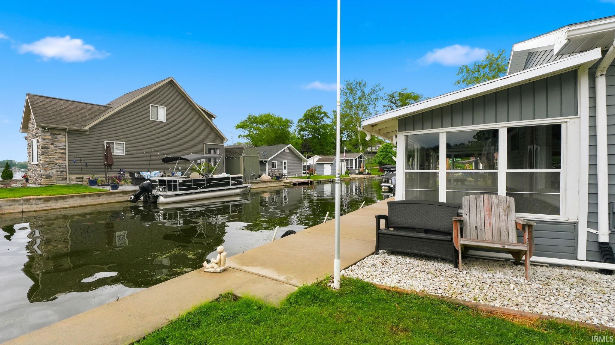 Waterfront property featuring a concrete dock, a stone-clad exterior accent, horizontal siding, and multiple windows