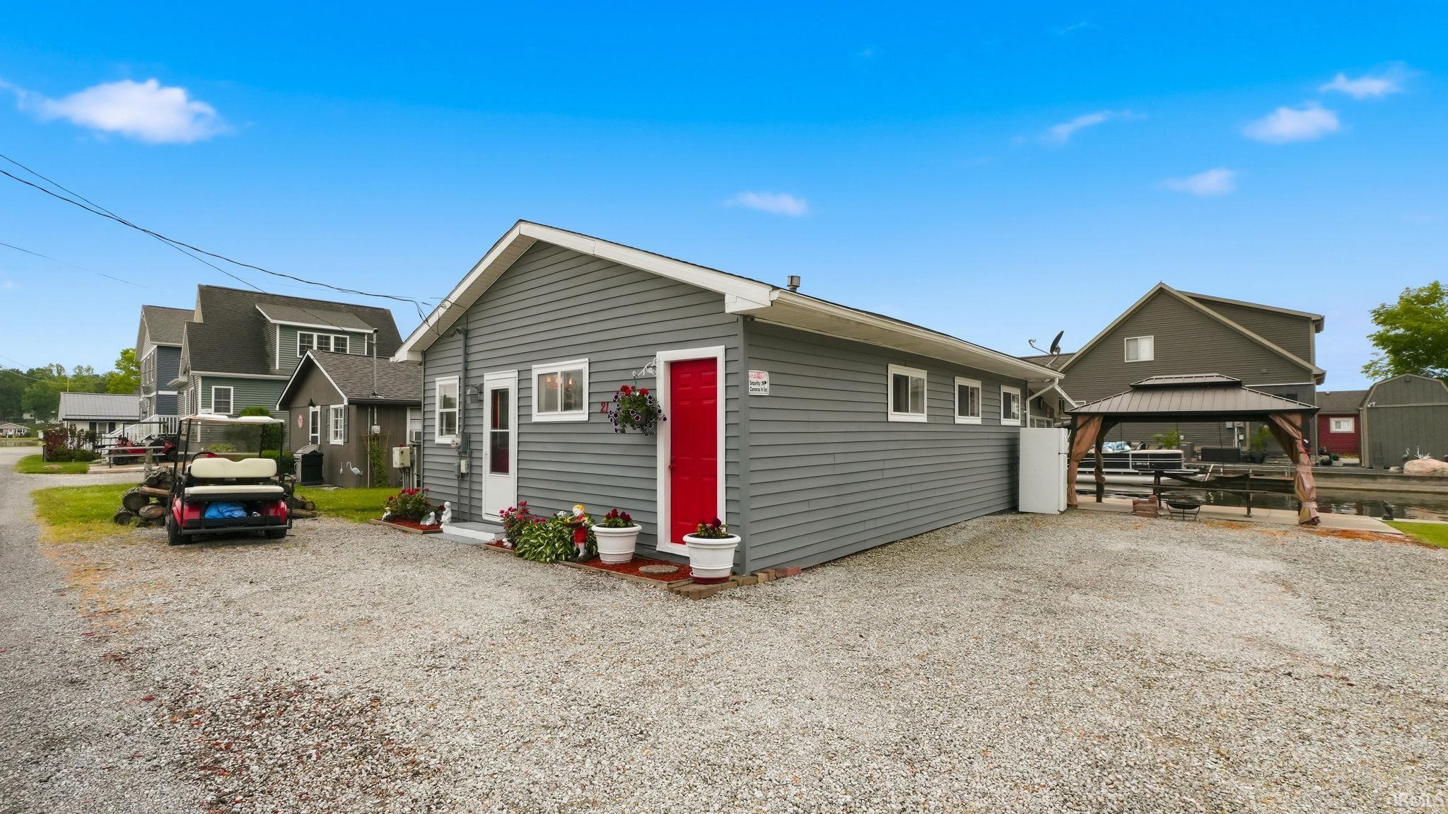 Gray horizontal siding exterior with white trim and a vibrant red entry door