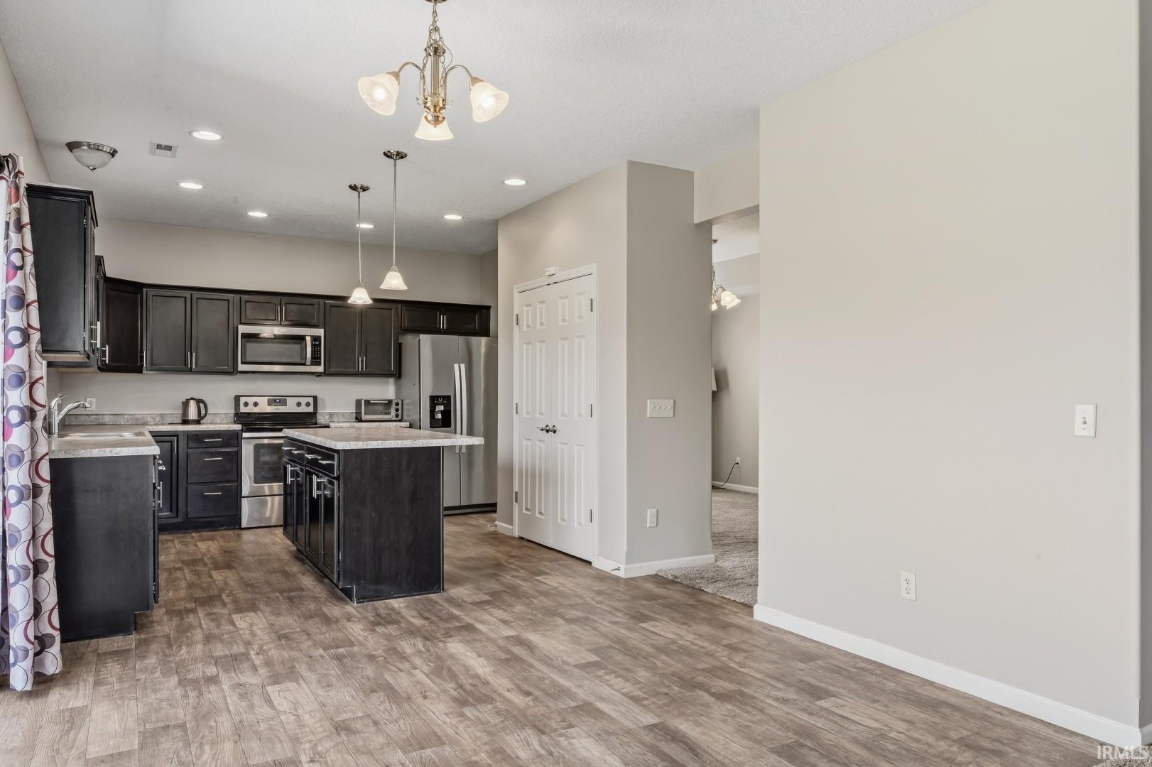 Kitchen featuring dark wood-finish cabinetry, stainless steel appliances, and wood-finish flooring