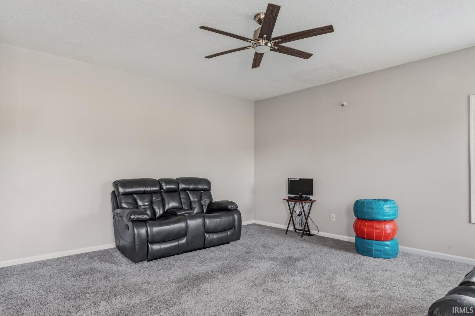 Neutral-toned walls complement the gray carpeting in this room, illuminated by a ceiling fan with integrated lighting