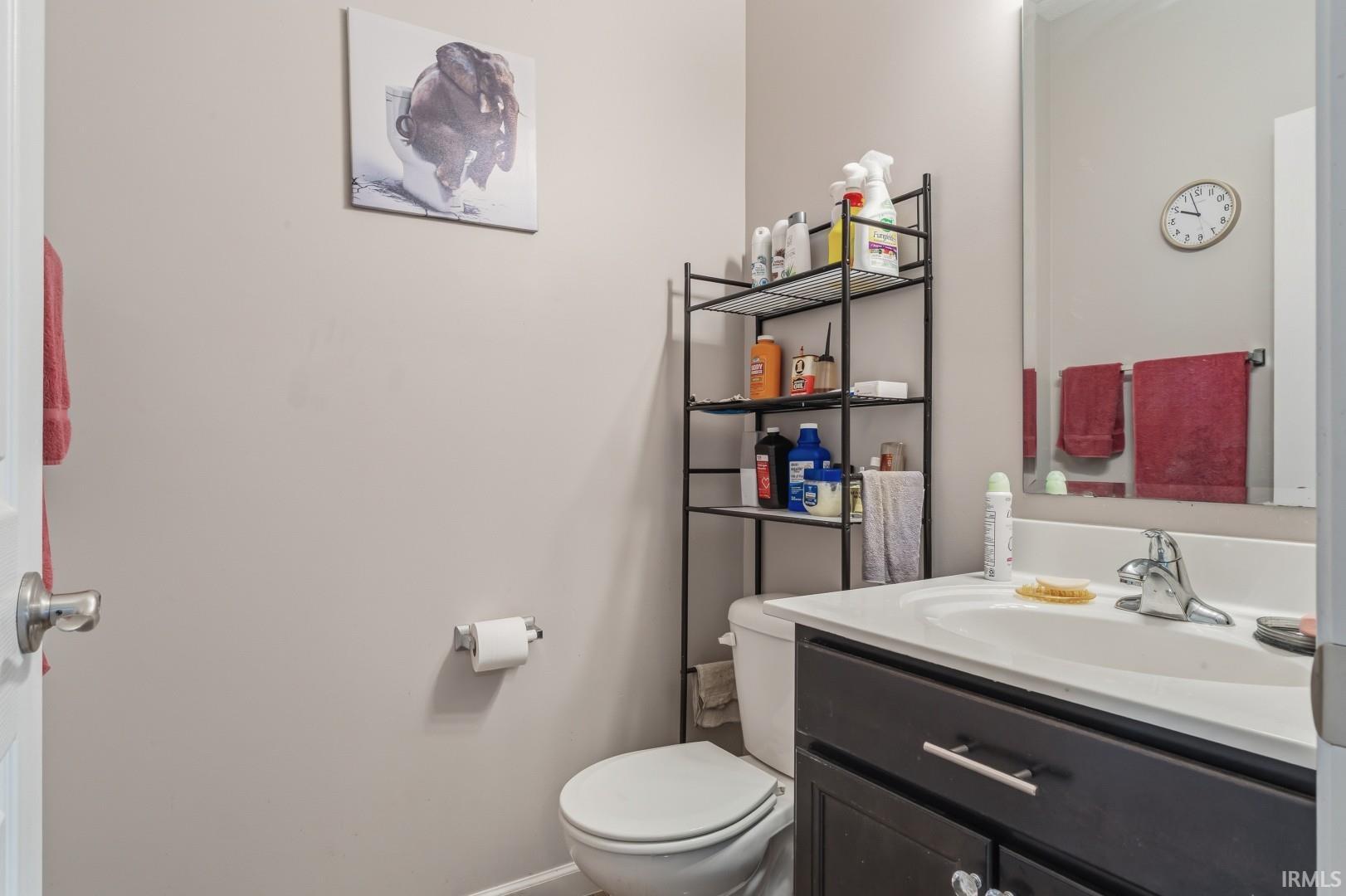 Bathroom featuring a dark wood-finish vanity with a white integrated sink, chrome faucet, and mirrored medicine cabinet