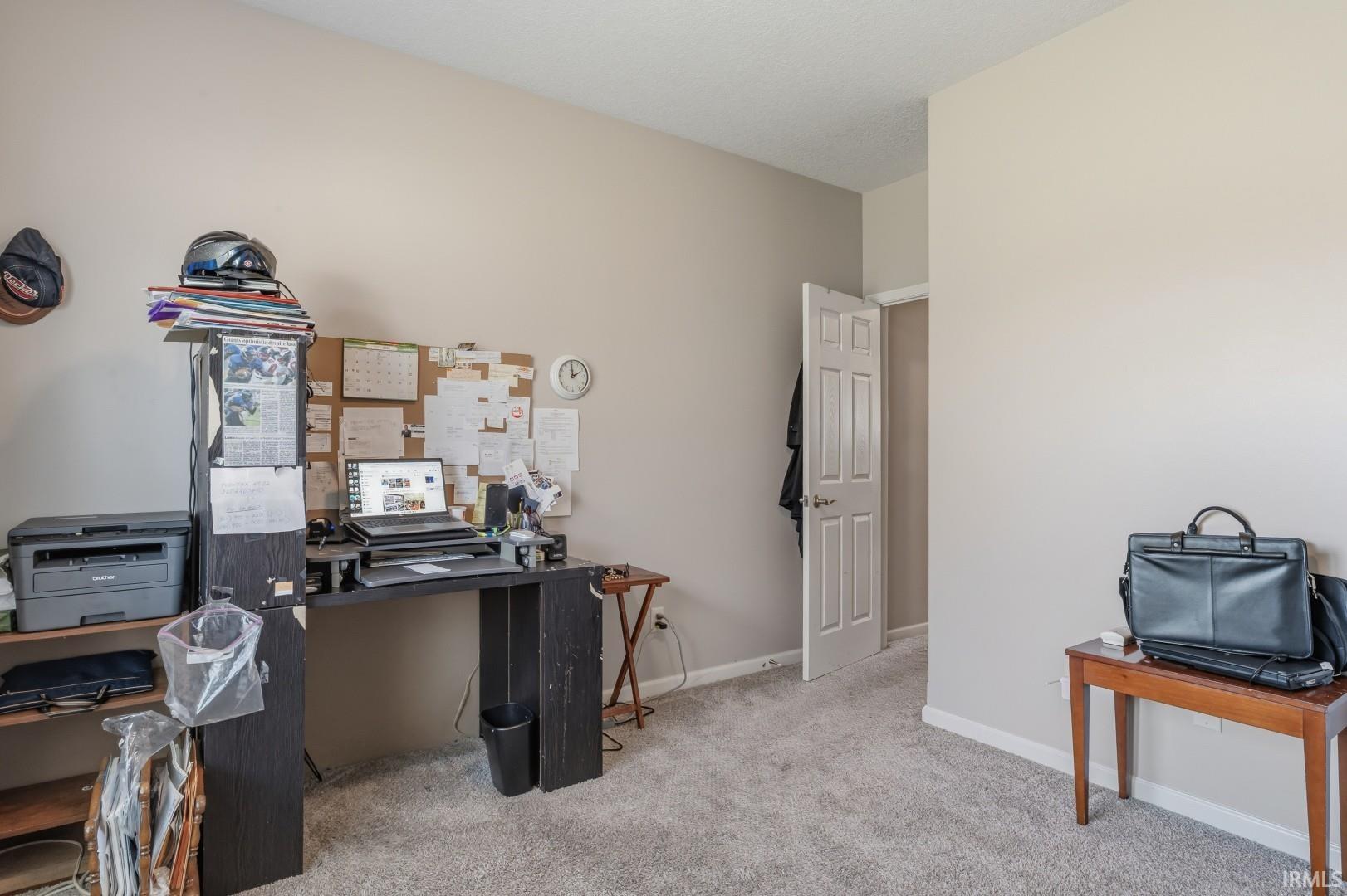 Carpeted room featuring light neutral wall paint and a standard white paneled door