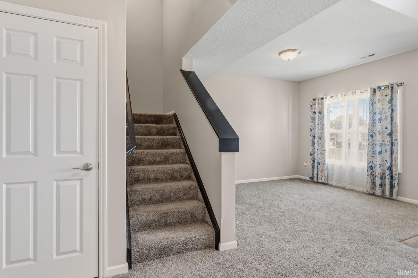 Carpeted staircase with dark wood-finish handrail