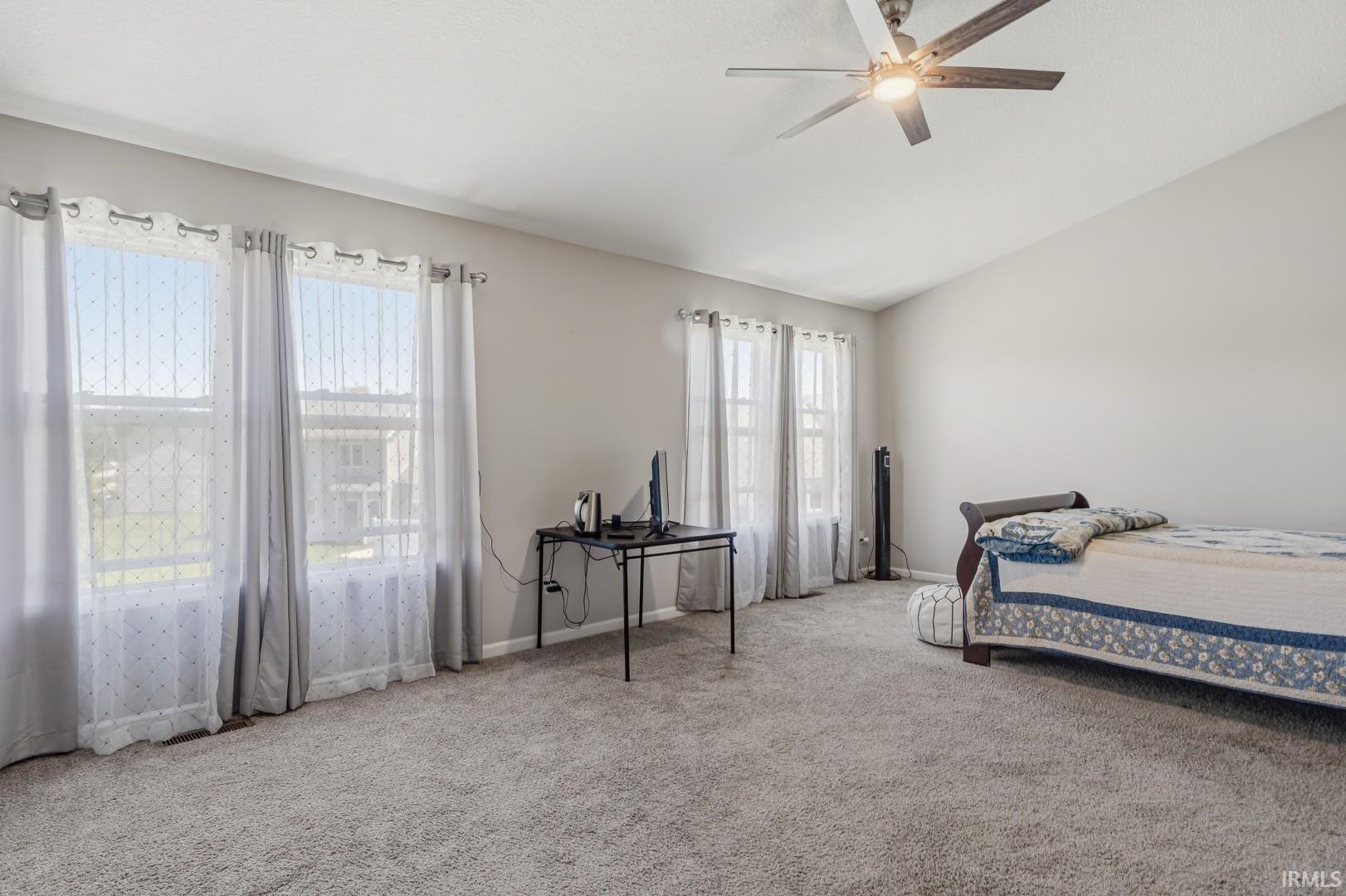 Spacious room featuring vaulted ceilings and light gray wall paint