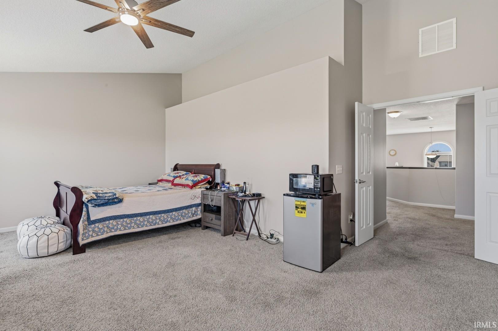 Spacious room featuring vaulted ceilings, a ceiling fan with light, and light-toned carpeting