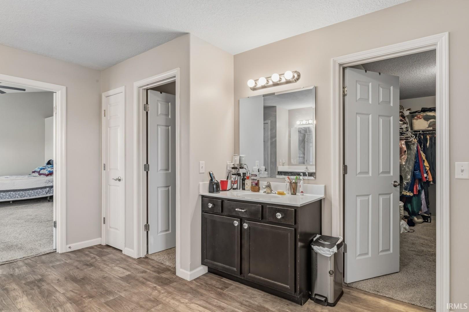 Vanity area featuring a dark wood-finish cabinet with a light-colored countertop, an overhead vanity light fixture, and a wall-mounted mirror