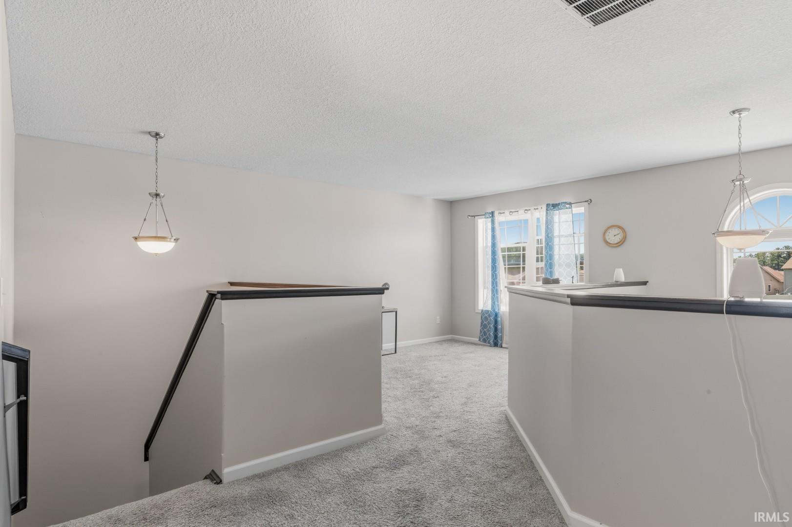 Carpeted landing featuring a half wall with dark cap, painted walls, and a single window with arched transom