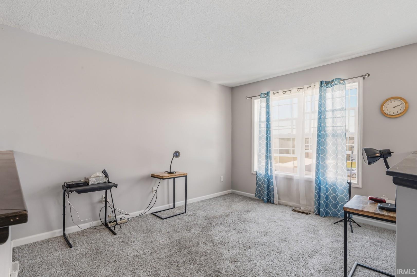 Carpeted interior space featuring light gray walls and a large window